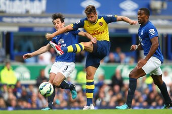 LIVERPOOL, ENGLAND - AUGUST 23:  Olivier Giroud of Arsenal shoots at goal under pressure from Leighton Baines  and Sylvain Distin of Everton during the Barclays Premier League match between Everton and Arsenal at Goodison Park on August 23, 2014 in Liverp