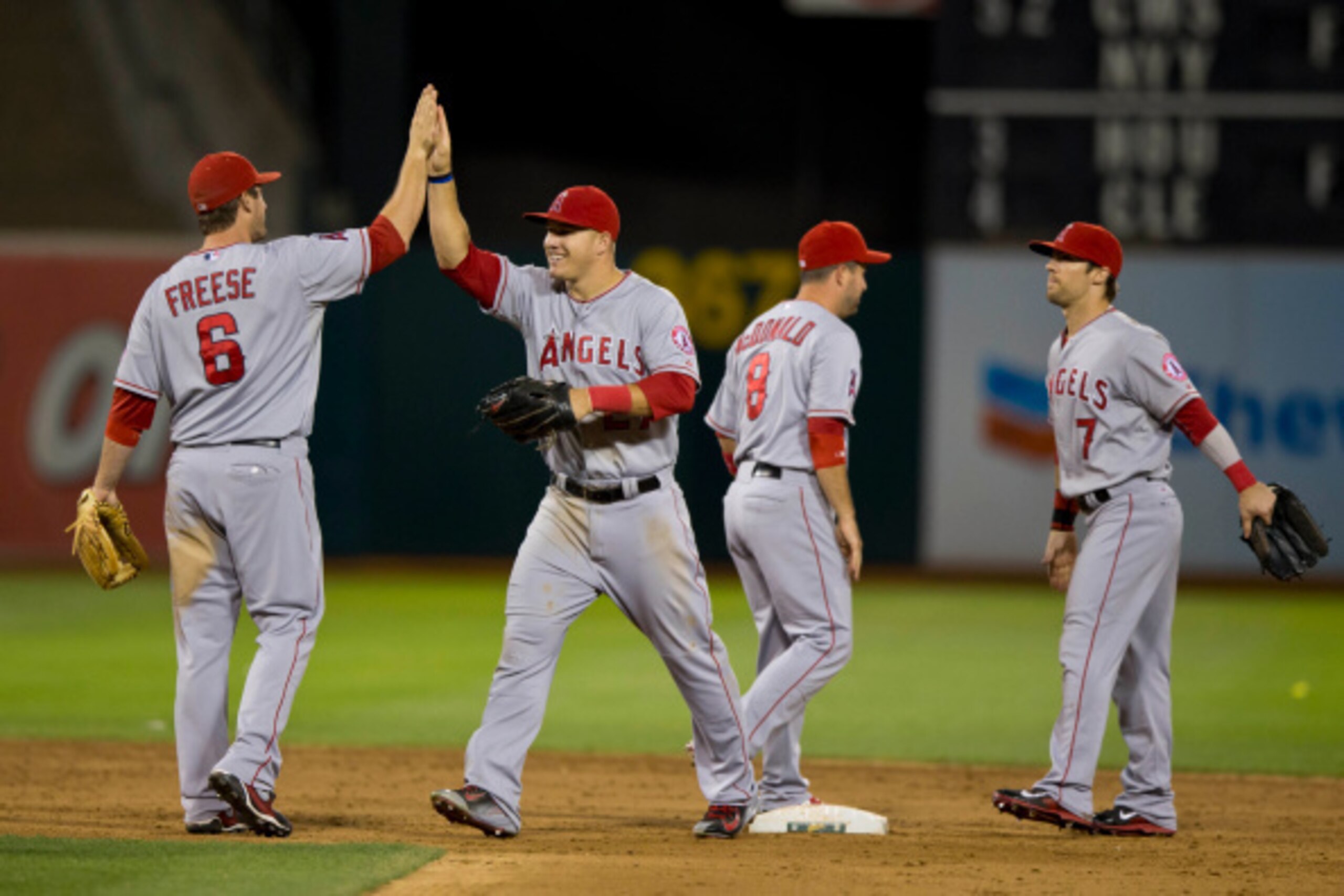 OAKLAND, CA - AUGUST 24:  David Freese #6 of the Los Angeles Angels of Anaheim celebrates with Mike Trout #27, John McDonald #8 and Collin Cowgill #7 after the game against the Oakland Athletics at O.co Coliseum on August 24, 2014 in Oakland, California. 