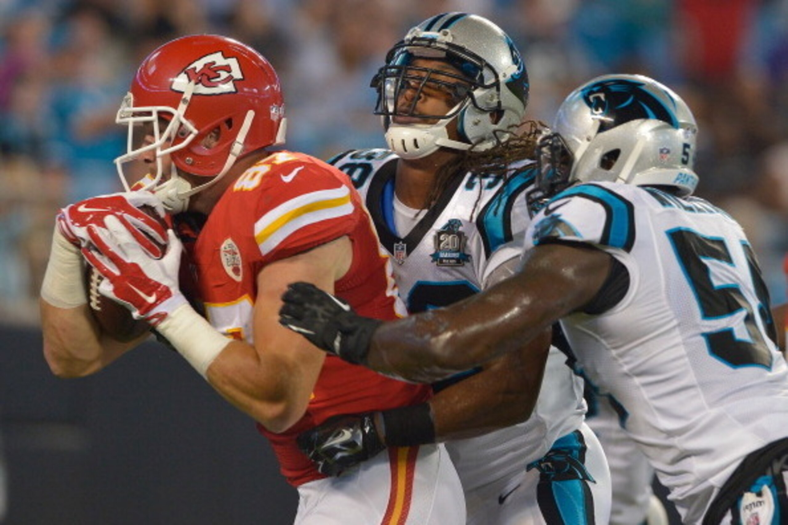 CHARLOTTE, NC - AUGUST 17:  Travis Kelce #87 of the Kansas City Chiefs drags Robert Lester #38 and Jason Williams #54 of the Carolina Panthers into the end zone for a touchdown during their game at Bank of America Stadium on August 17, 2014 in Charlotte, 