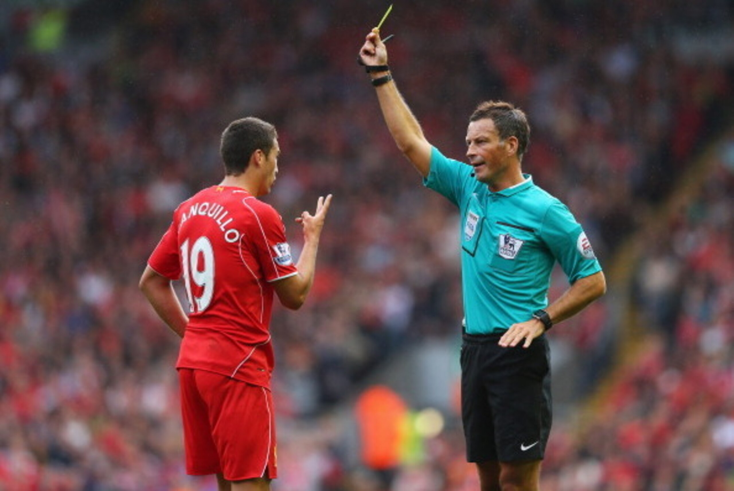 LIVERPOOL, ENGLAND - AUGUST 17: Referee Mark Clattenburg shows the yellow card to Javi Manquillo of Liverpool during the Barclays Premier League match between Liverpool and Southampton at Anfield on August 17, 2014 in Liverpool, England.  (Photo by Alex L