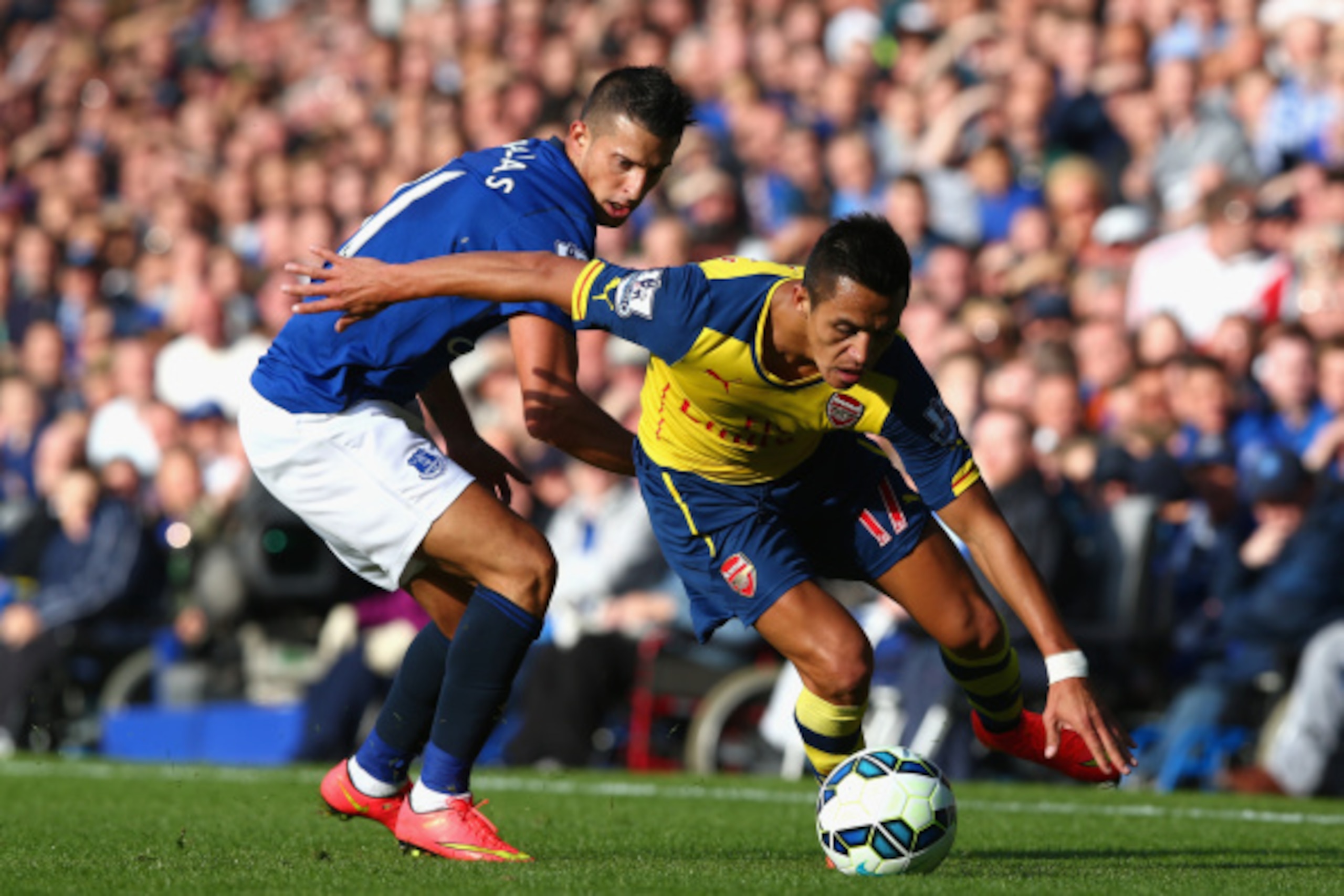 LIVERPOOL, ENGLAND - AUGUST 23:  Alexis Sanchez of Arsenal competes with Kevin Mirallas of Everton during the Barclays Premier League match between Everton and Arsenal at Goodison Park on August 23, 2014 in Liverpool, England.  (Photo by Clive Brunskill/G