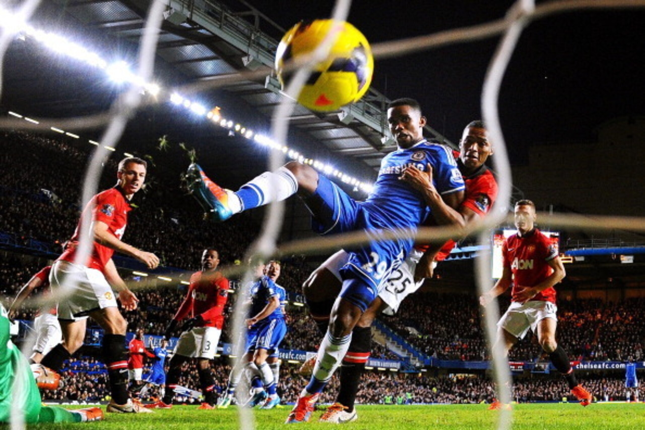LONDON, ENGLAND - JANUARY 19:   (EDITORS NOTE: Retransmission of #463789677 with alternate crop.) Samuel Eto'o of Chelsea scores his team's third goal and completes his hat trick despite the challenge from Antonio Valencia of Manchester United during the 