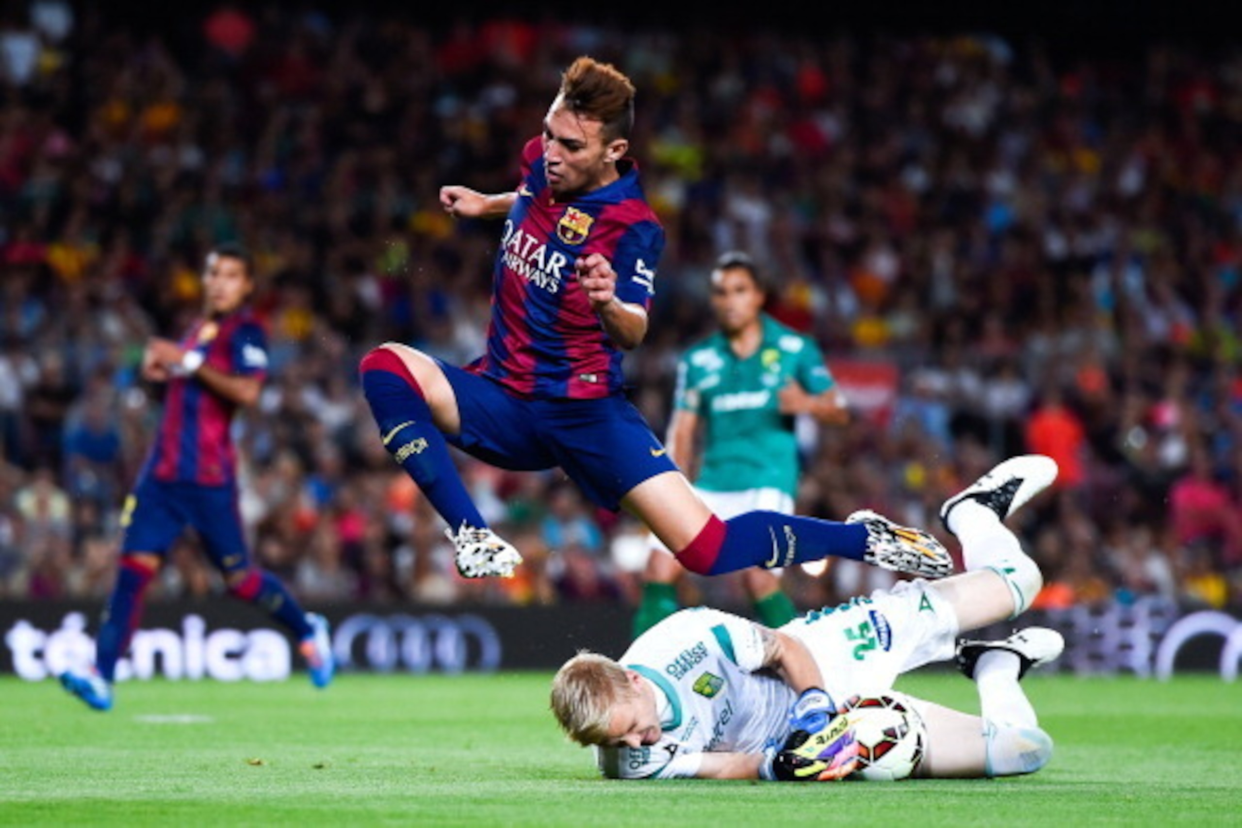 BARCELONA, SPAIN - AUGUST 18:  Munir jumps over Christian Martinez of Club Leon during the Joan Gamper Trophy match between FC Barcelona and Club Leon at Camp Nou on August 18, 2014 in Barcelona, Spain.  (Photo by David Ramos/Getty Images)