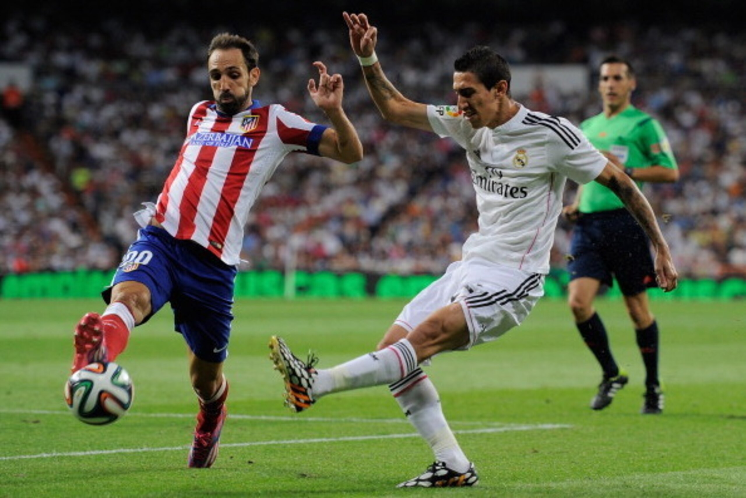MADRID, SPAIN - AUGUST 19:  Angel di Maria (R) of Real Madrid shoots past Raul Garcia of Club Atletico de Madrid during the Supercopa first leg match between Real Madrid and Club Atletico de Madrid at Estadio Santiago Bernabeu on August 19, 2014 in Madrid