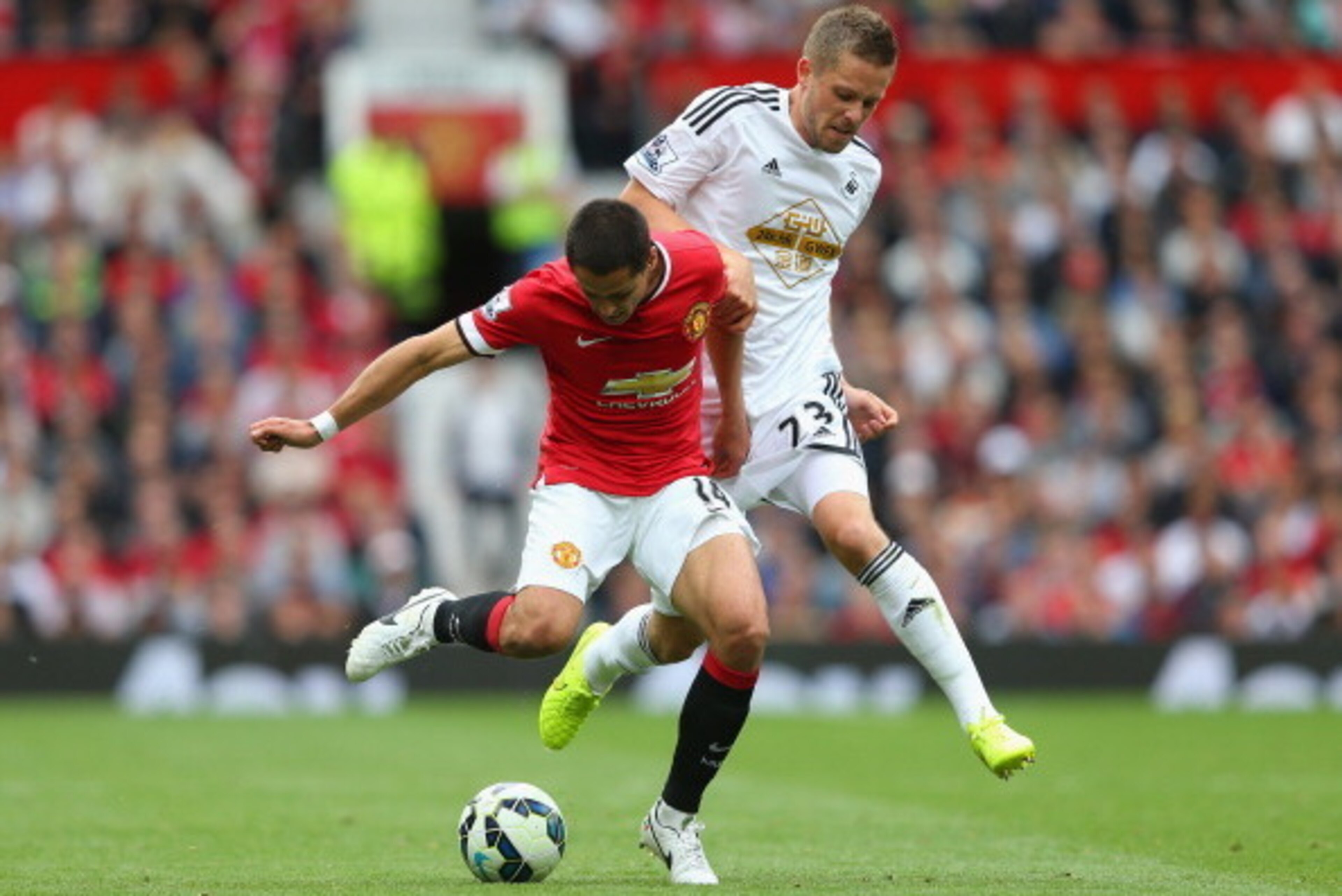 MANCHESTER, ENGLAND - AUGUST 16:  Javier Hernandez of Manchester United competes with Gylfi Sigurdsson of Swansea City during the Barclays Premier League match between Manchester United and Swansea City at Old Trafford on August 16, 2014 in Manchester, En