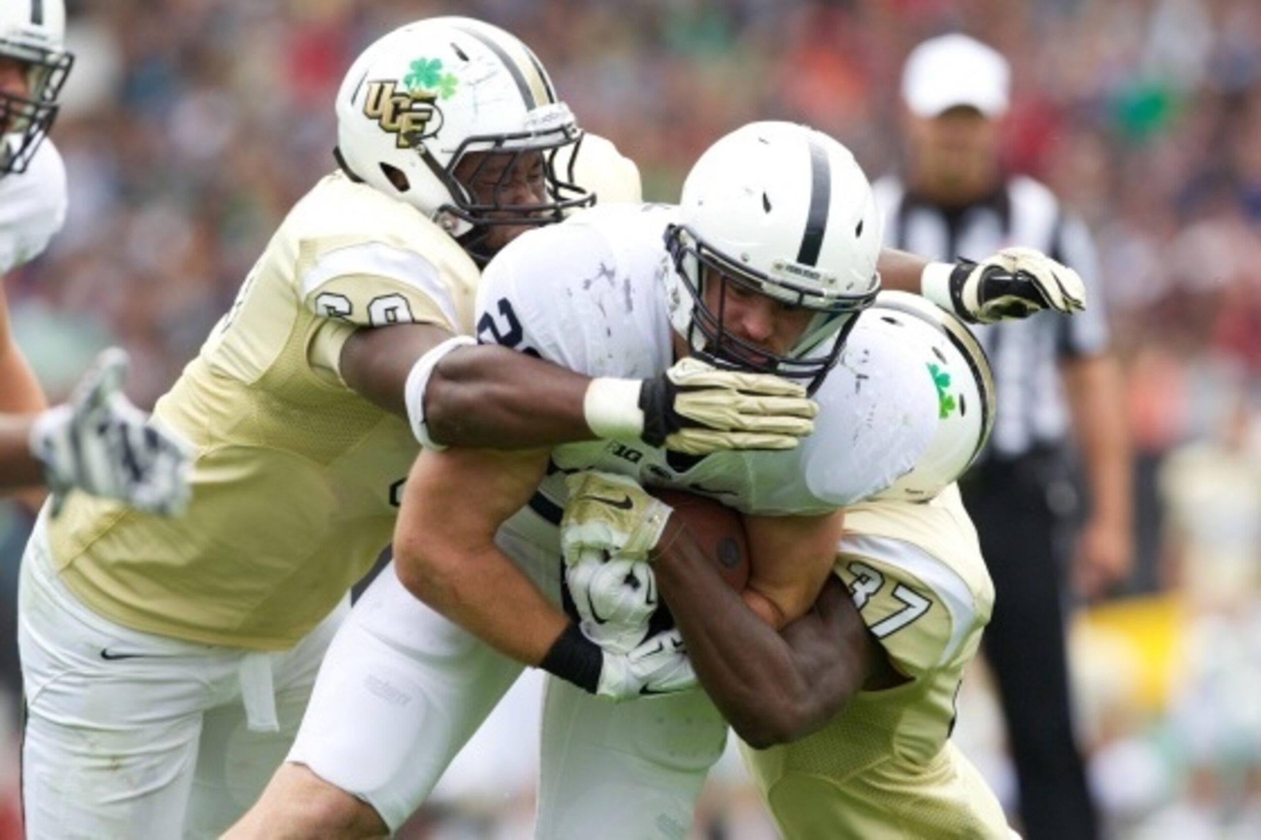 DUBLIN, IRELAND - AUGUST 30:   Zach Zwinak #28 of Penn State is tackled by Thomas Niles #69 and Brandon Alexander #37 of UCF during the Croke Park Classic American Football match between Penn State v Central Florida at Croke Park Stadium on August 30, 201