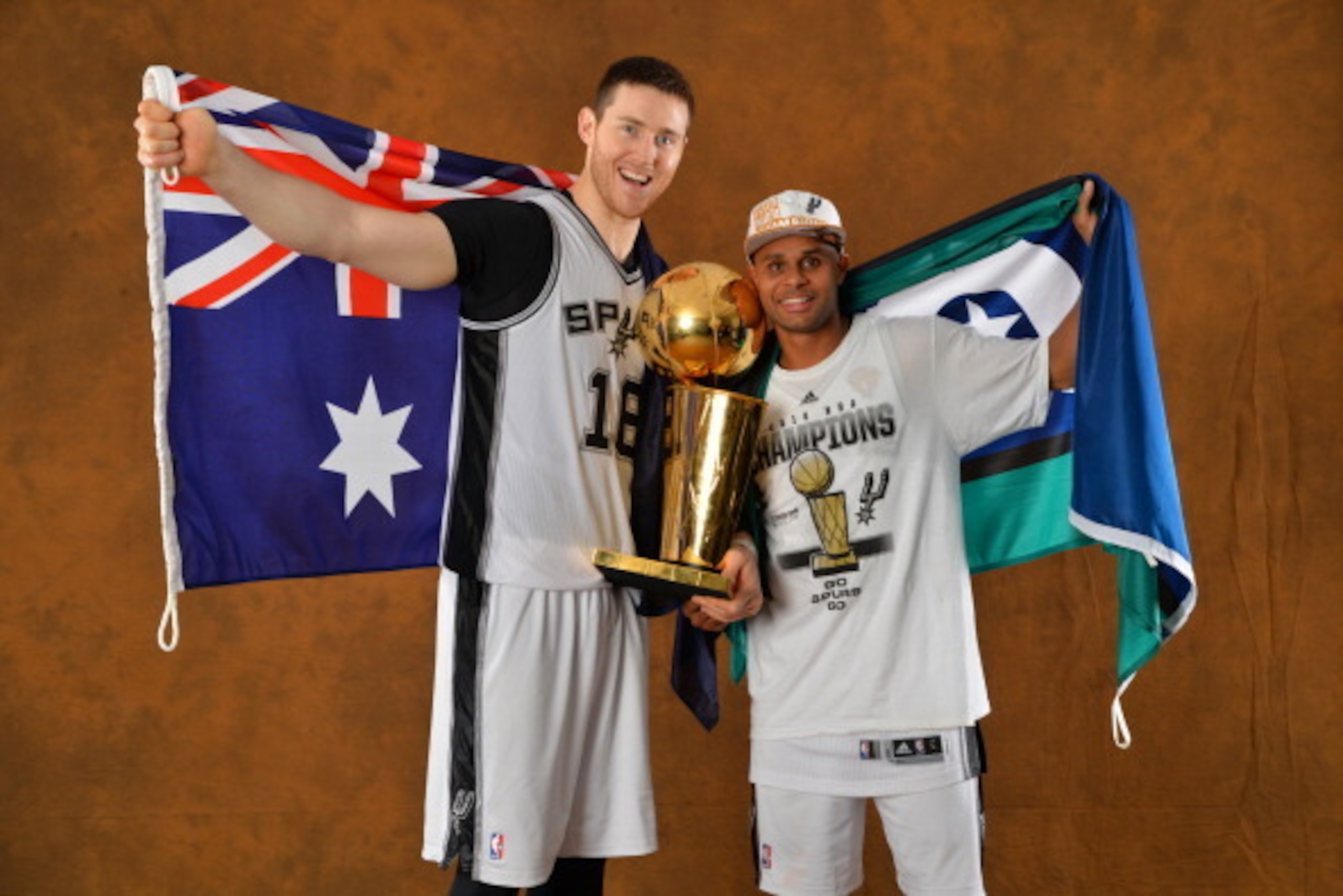 SAN ANTONIO, TX - JUNE 15: Aron Baynes and Patty Mills of the San Antonio Spurs poses for a portrait with the Larry O'Brien Trophy after defeating the Miami Heat in Game Five of the 2014 NBA Finals on June 15, 2014 at AT&T Center in San Antonio, Texas. NO