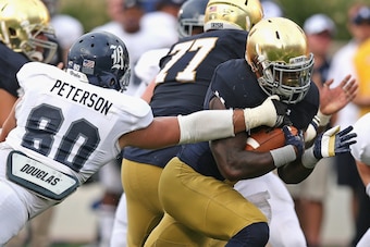 SOUTH BEND, IN - AUGUST 30:  Greg Bryant #1 of the Notre Dame Fighting Irish breaks a tackle attempt by Grant Peterson #80 of the Rice Owls on a 17 yard touchdown run at Notre Dame Stadium on August 30, 2014 in South Bend, Indiana. Notre Dame defeated Ric