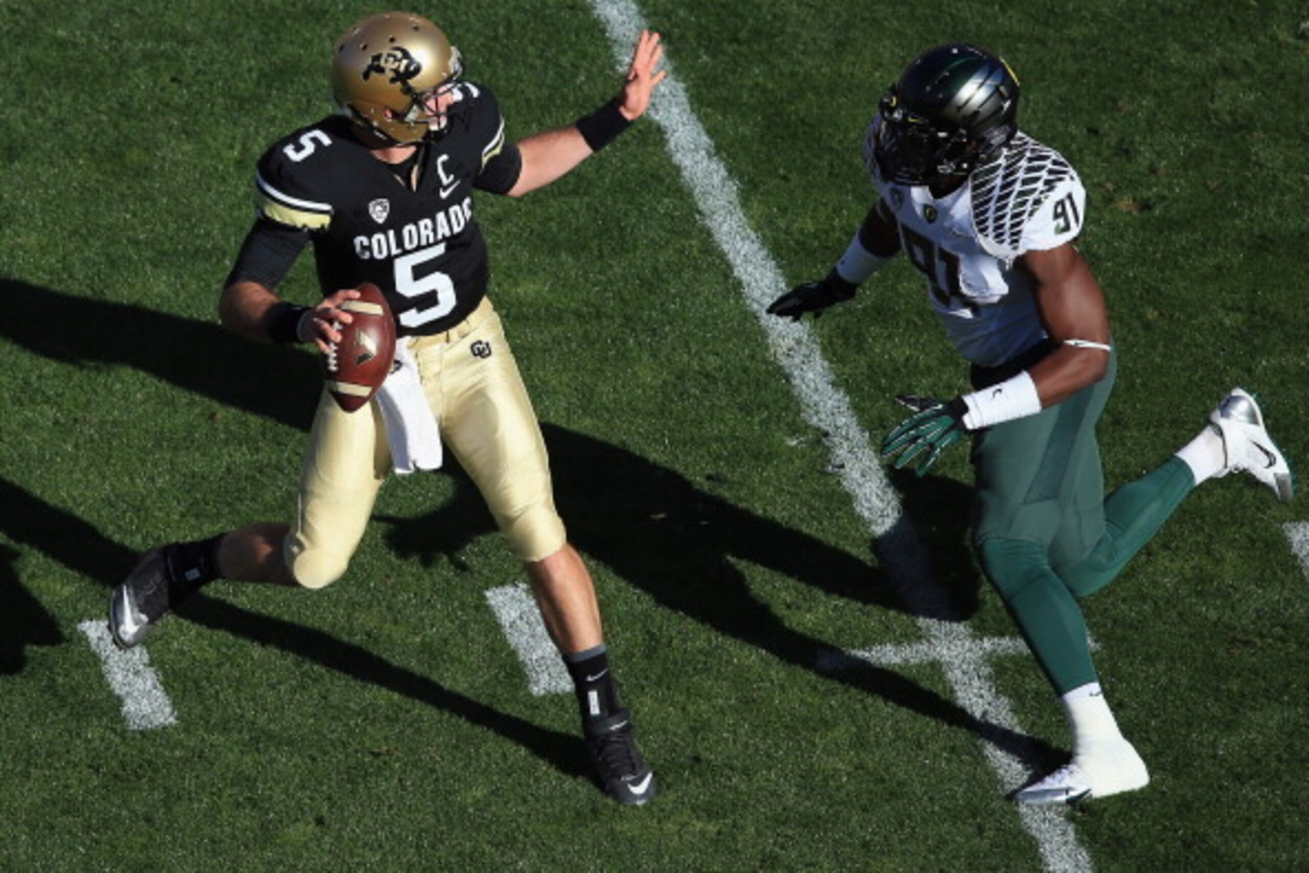 BOULDER, CO - OCTOBER 05:  Quarterback Connor Wood #5 of the Colorado Buffaloes scramble to elude defensive end Tony Washington #91 of the Oregon Ducks at Folsom Field on October 5, 2013 in Boulder, Colorado. The Ducks defeated the Buffs 57-16.  (Photo by