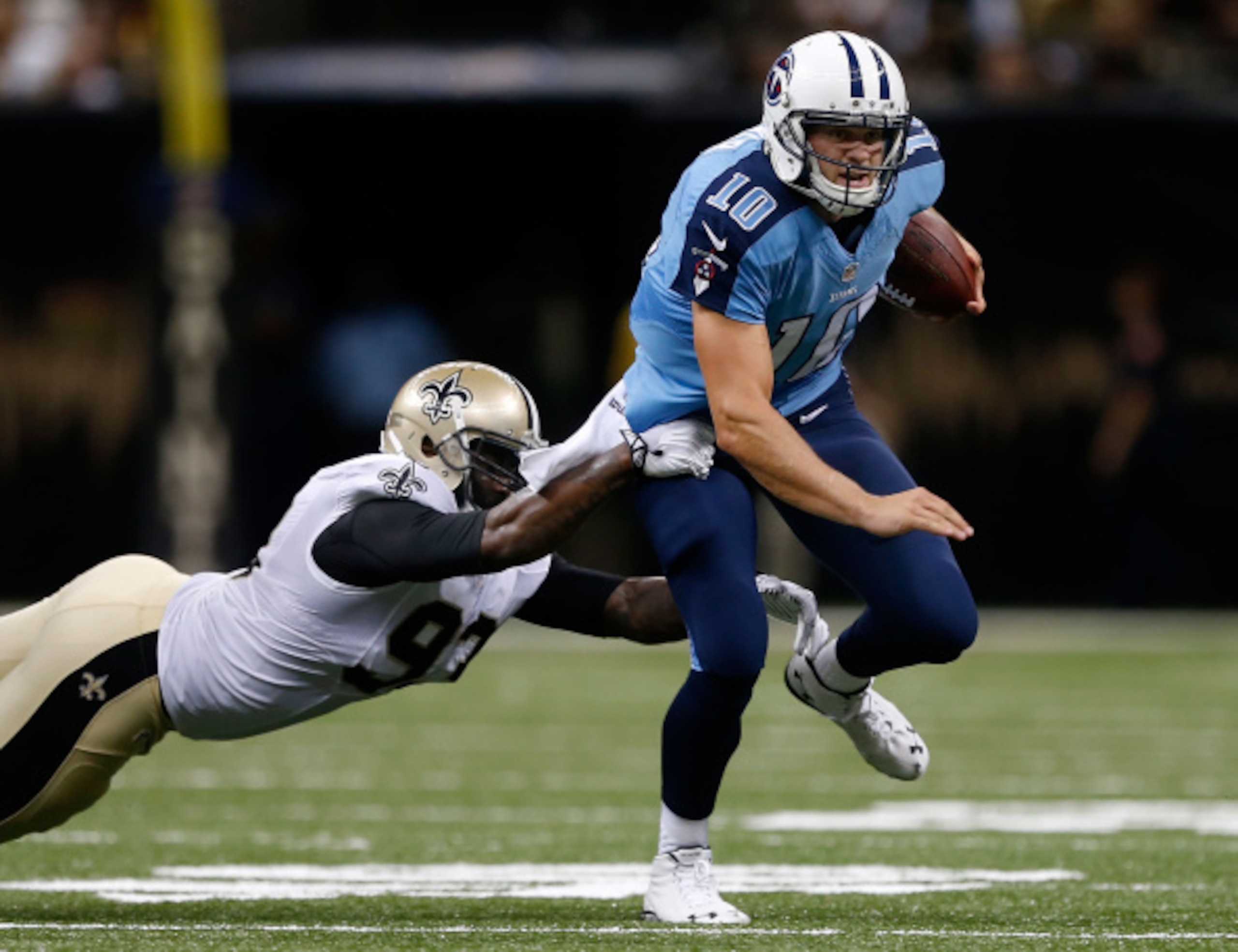 NEW ORLEANS, LA - AUGUST 15:  Junior Galette #93 of the New Orleans Saints tackles Jake Locker #10 of the Tennessee Titans during a preseason game between the New Orleans Saints and the Tennessee Titans at Mercedes-Benz Superdome on August 15, 2014 in New