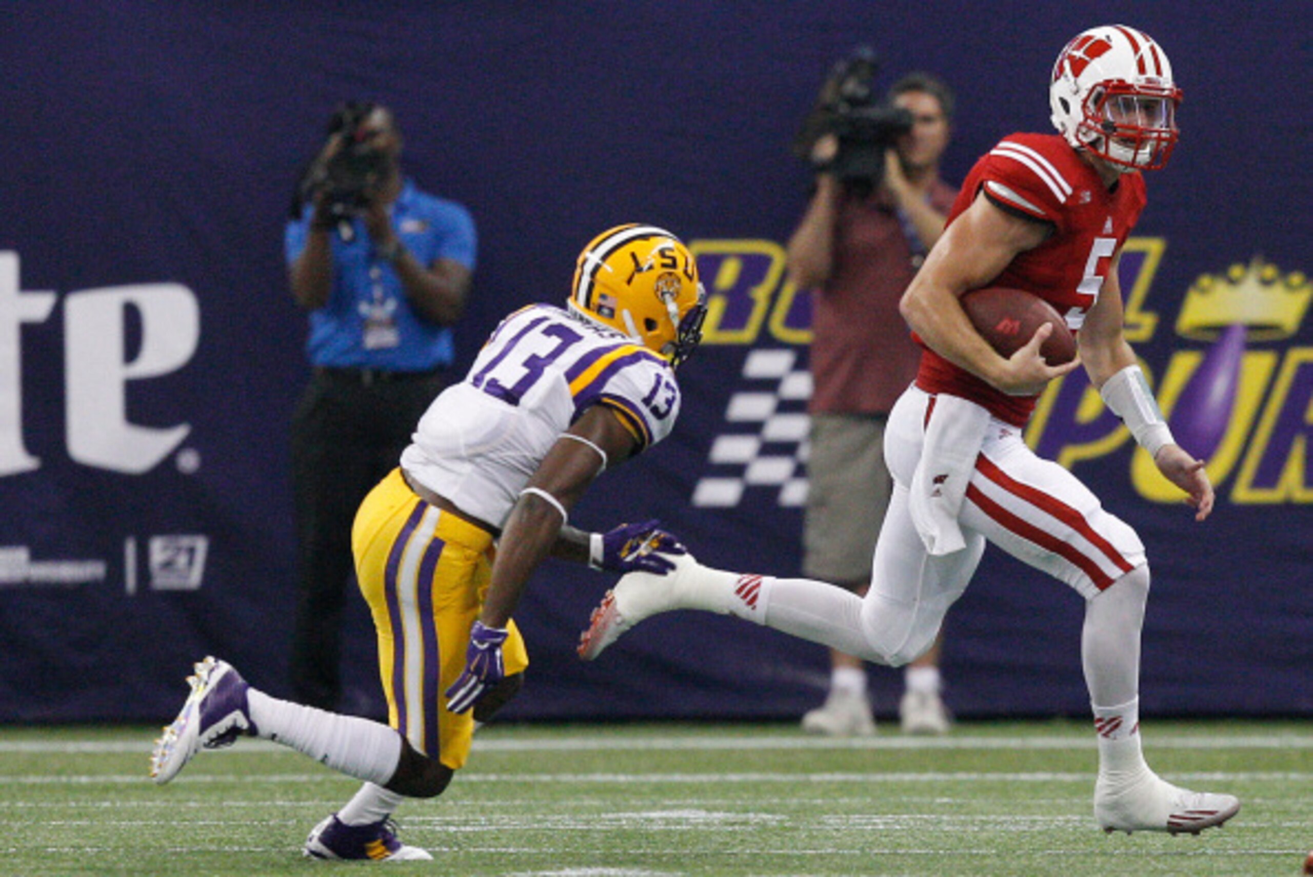 HOUSTON, TX - AUGUST 30:  Tanner McEvoy #5 of the Wisconsin Badgers scrambles out of the pocket as he is pursued by Dwayne Thomas #13 of the LSU Tigers at NRG Stadium on August 30, 2014 in Houston, Texas.  (Photo by Bob Levey/Getty Images)