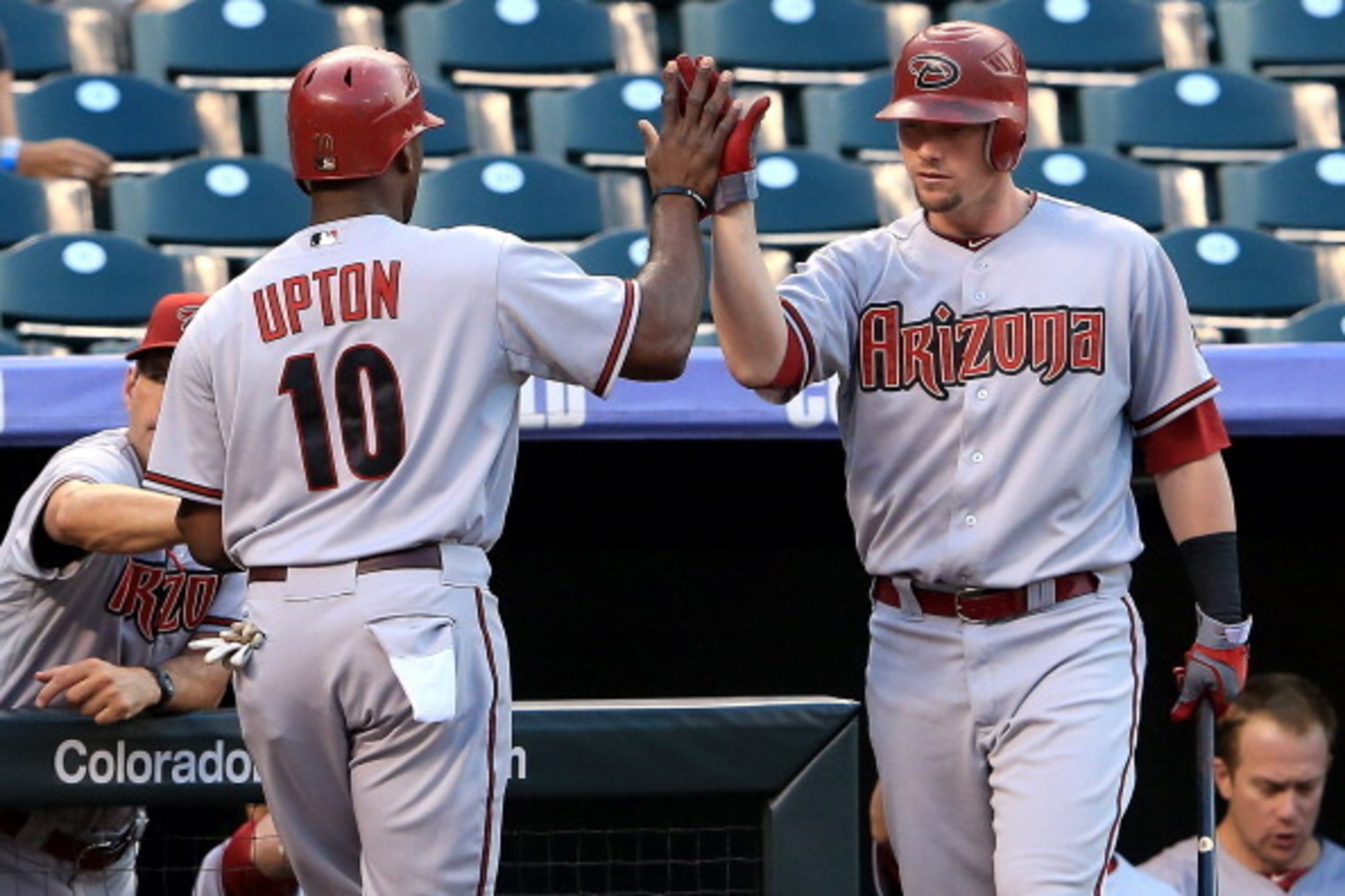 DENVER, CO - SEPTEMBER 21:  Justin Upton #10 of the Arizona Diamondbacks is welcomed back to the dugout by Chris Johnson #28 after Upton scored on a double by Paul Goldschmidt against the Colorado Rockies in the first inning at Coors Field on September 21