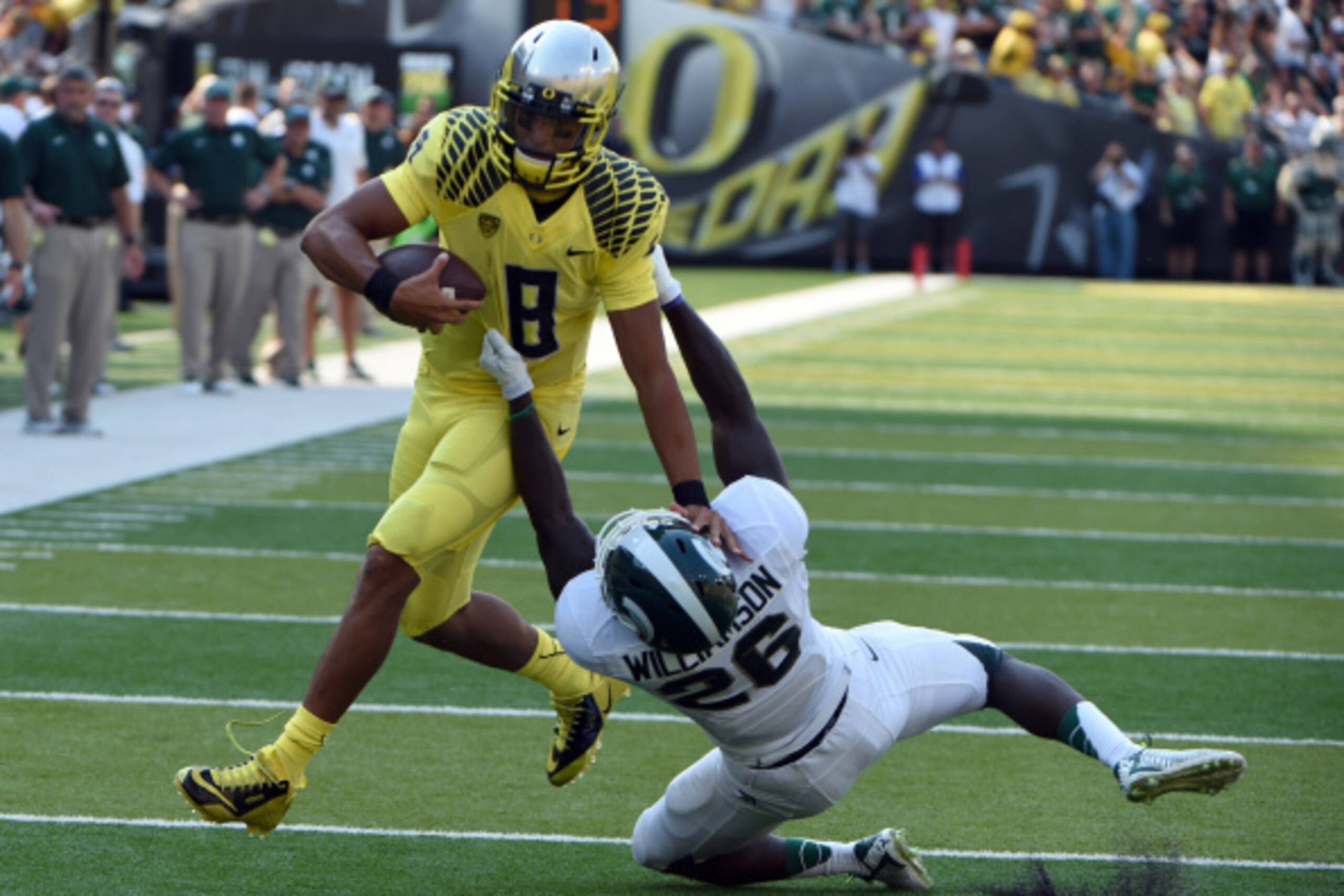EUGENE, OR -SEPTEMBER 06; Quarterback Marcus Mariota #8 of the Oregon Ducks is brought down by safety RJ Williamson #26 of the Michigan State Spartans in the first quarter of the game at Autzen Stadium on September 6, 2014 in Eugene, Oregon. (Photo by Ste