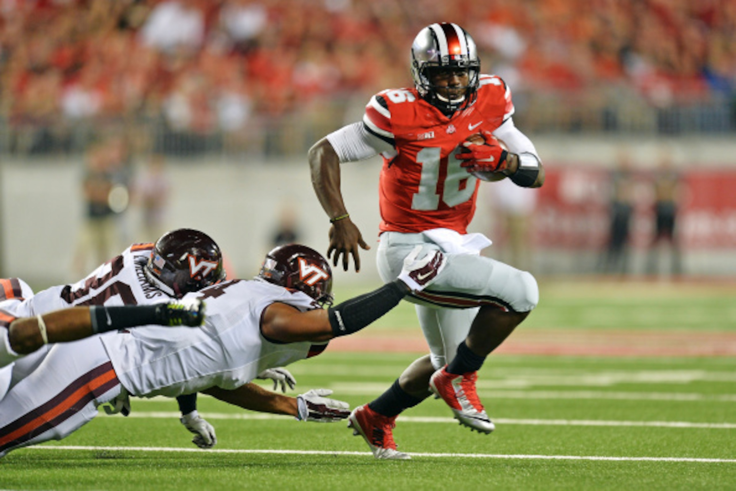 COLUMBUS, OH - SEPTEMBER 6:  J.T. Barrett #16 of the Ohio State Buckeyes eludes a Virginia Tech tackler in the first quarter as he picks up yardage at Ohio Stadium on September 6, 2014 in Columbus, Ohio.  (Photo by Jamie Sabau/Getty Images)
