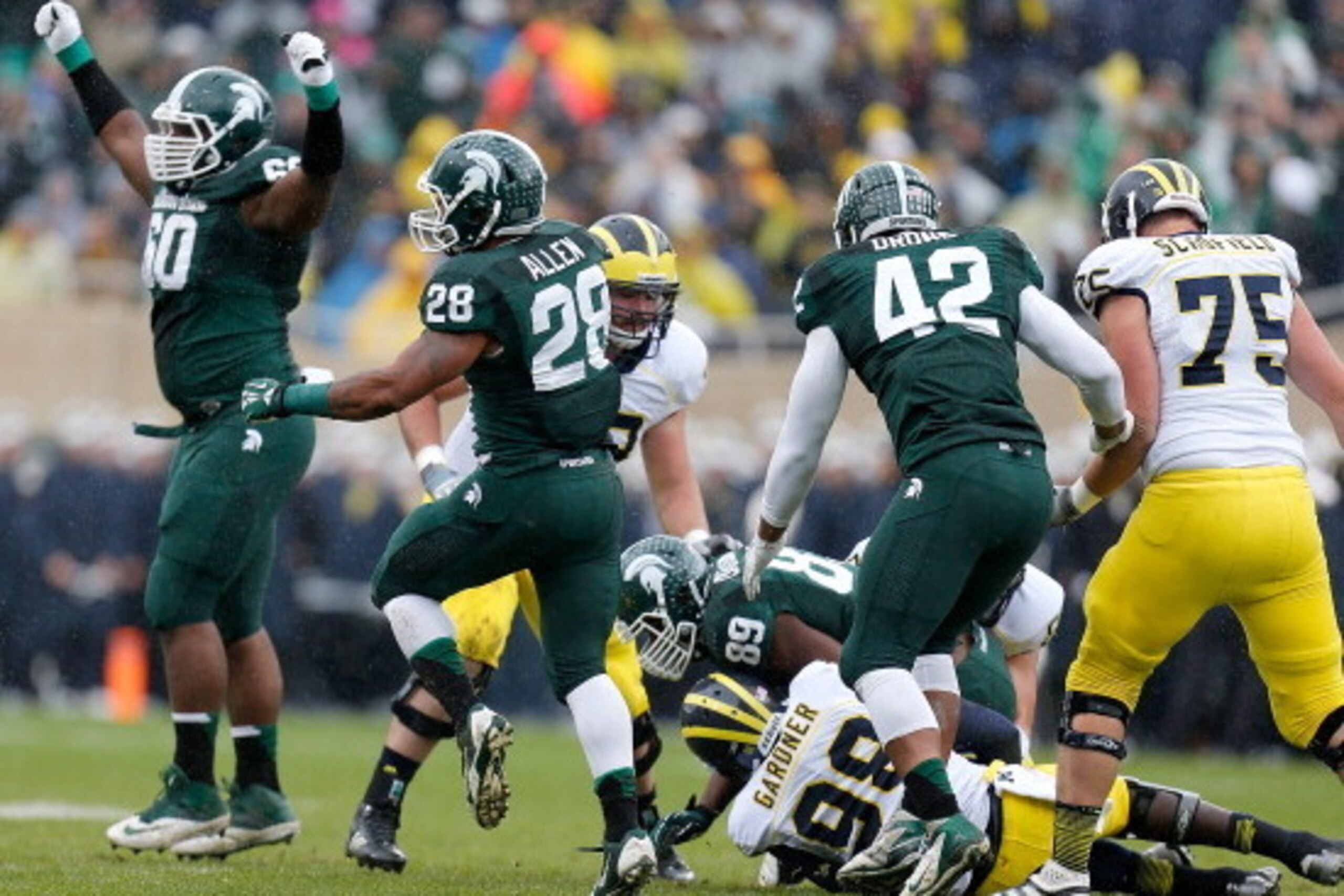 EAST LANSING, MI - NOVEMBER 02:  Devin Gardner #98 of the Michigan Wolverines is sacked by Shilique Calhoun #89 of the Michigan State Spartans as teammates Micajah Reynolds #60 and Denicos Allen #28 celebrate in the first quarter at Spartan Stadium on Nov