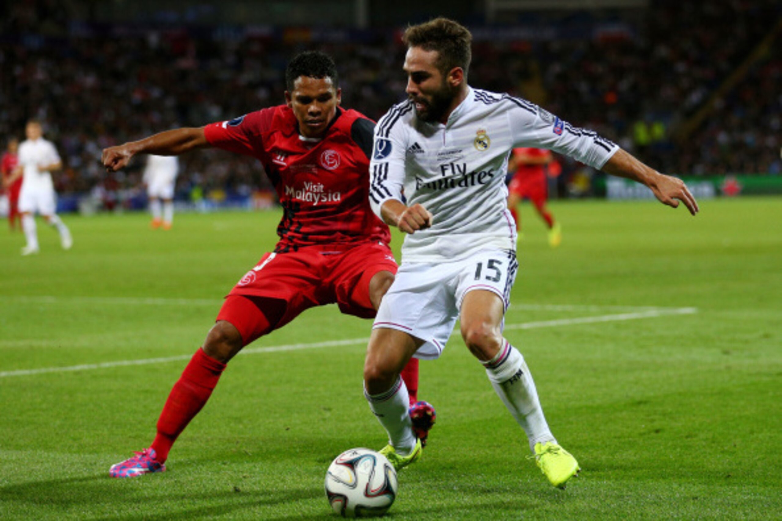 CARDIFF, WALES - AUGUST 12:  Dani Carvajal of Real Madrid is closed down by Carlos Bacca of Sevilla during the UEFA Super Cup between Real Madrid and Sevilla FC at Cardiff City Stadium on August 12, 2014 in Cardiff, Wales.  (Photo by Clive Mason/Getty Ima
