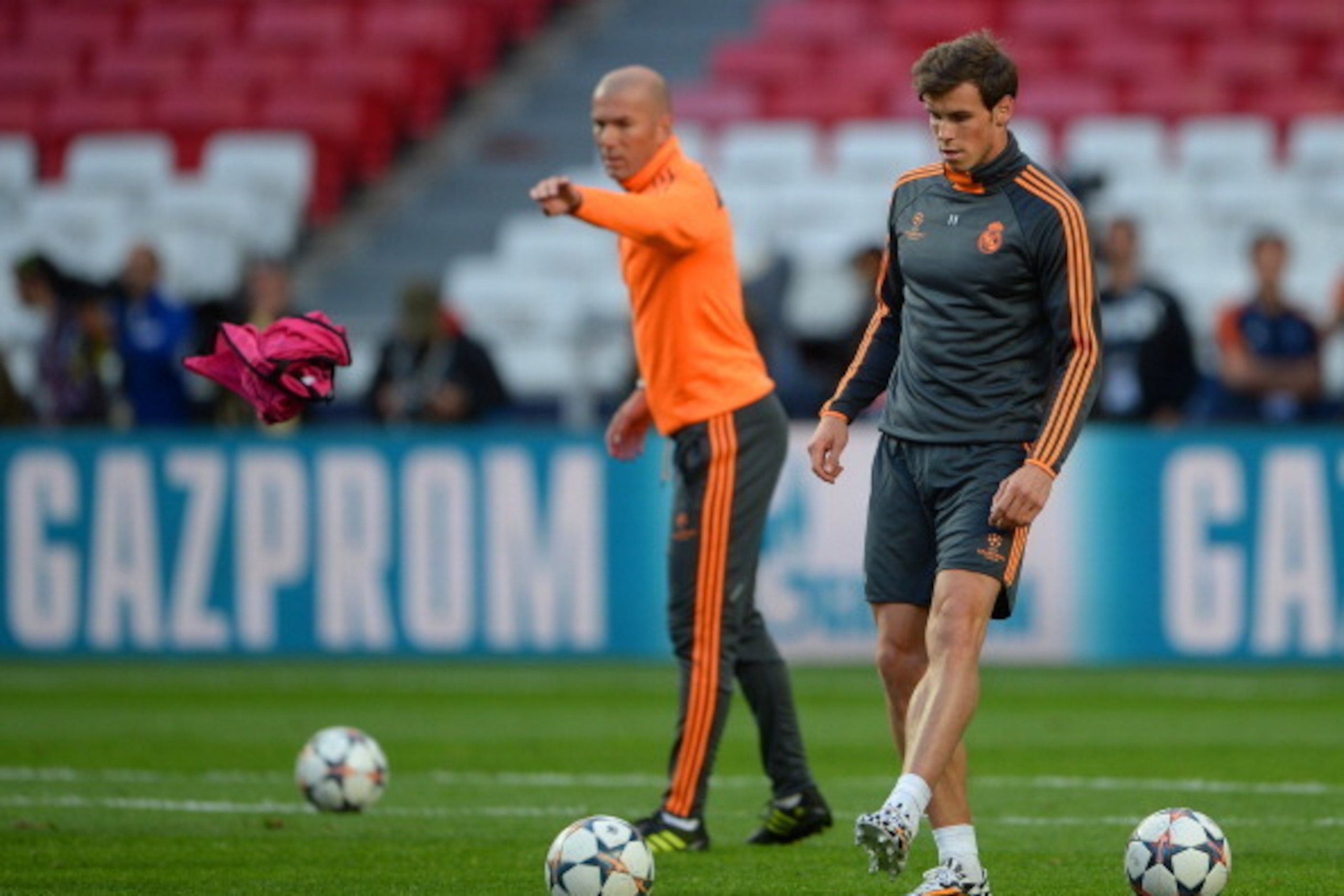 LISBON, PORTUGAL - MAY 23:  Gareth Bale of Real Madrid kicks the ball as Assistant coach Zinedine Zidane of Real Madrid throws a bib during a Real Madrid training session ahead of the UEFA Champions League Final against Club Atletico de Madrid at Estadio 