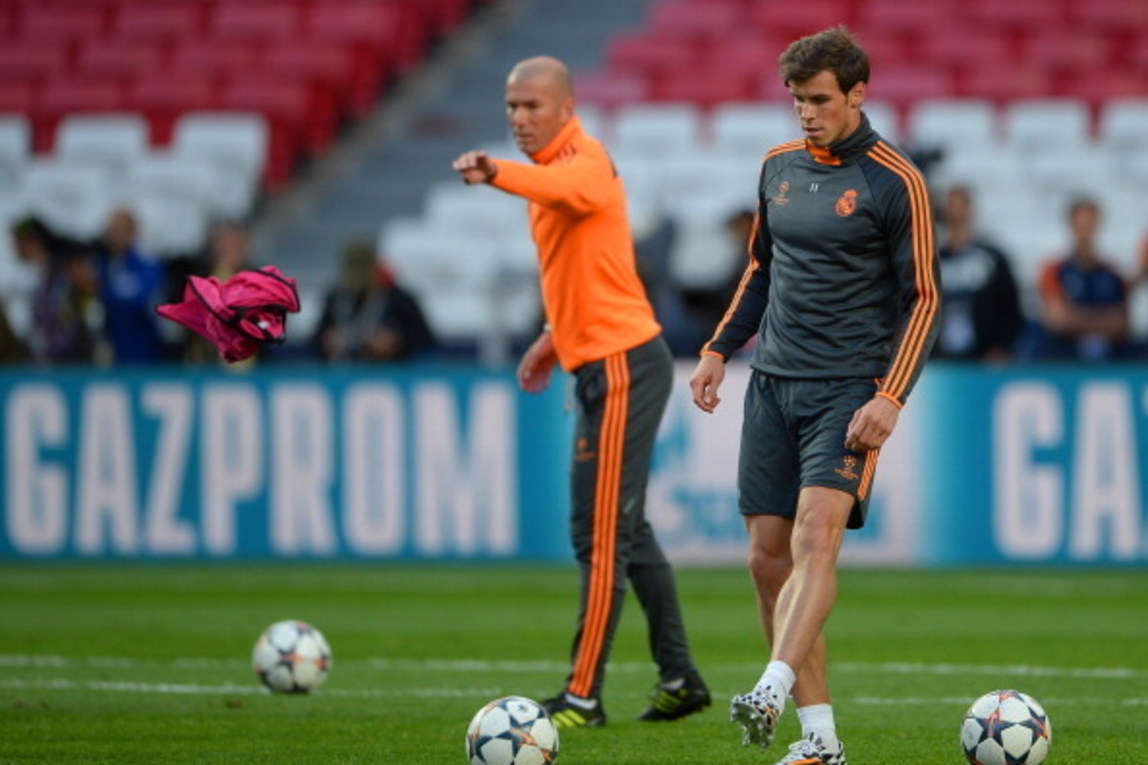LISBON, PORTUGAL - MAY 23:  Gareth Bale of Real Madrid kicks the ball as Assistant coach Zinedine Zidane of Real Madrid throws a bib during a Real Madrid training session ahead of the UEFA Champions League Final against Club Atletico de Madrid at Estadio 