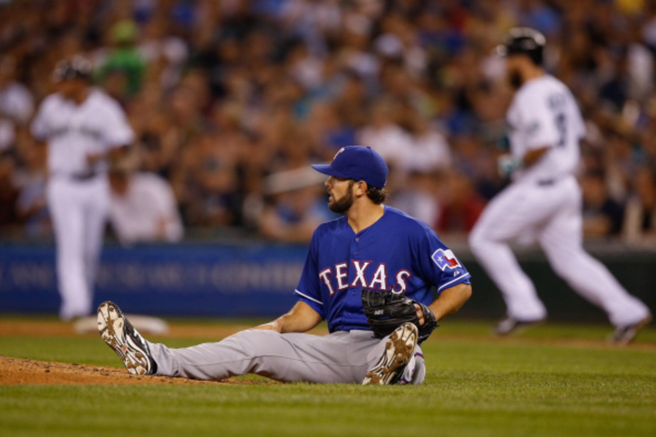 SEATTLE, WA - AUGUST 26:  Starting pitcher Nick Martinez #22 of the Texas Rangers sits on the grass after giving up an RBI single to Dustin Ackley #13 of the Seattle Mariners in the fourth inning at Safeco Field on August 26, 2014 in Seattle, Washington.