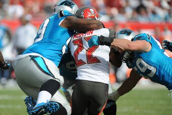 TAMPA, FL - SEPTEMBER 7: Running back Doug Martin #22 of the Tampa Bay Buccaneers is tackled by defensive tackle Kawann Short #99 and middle linebacker Luke Kuechly #59 of the Carolina Panthers at Raymond James Stadium on September 7, 2014 in Tampa, Flori