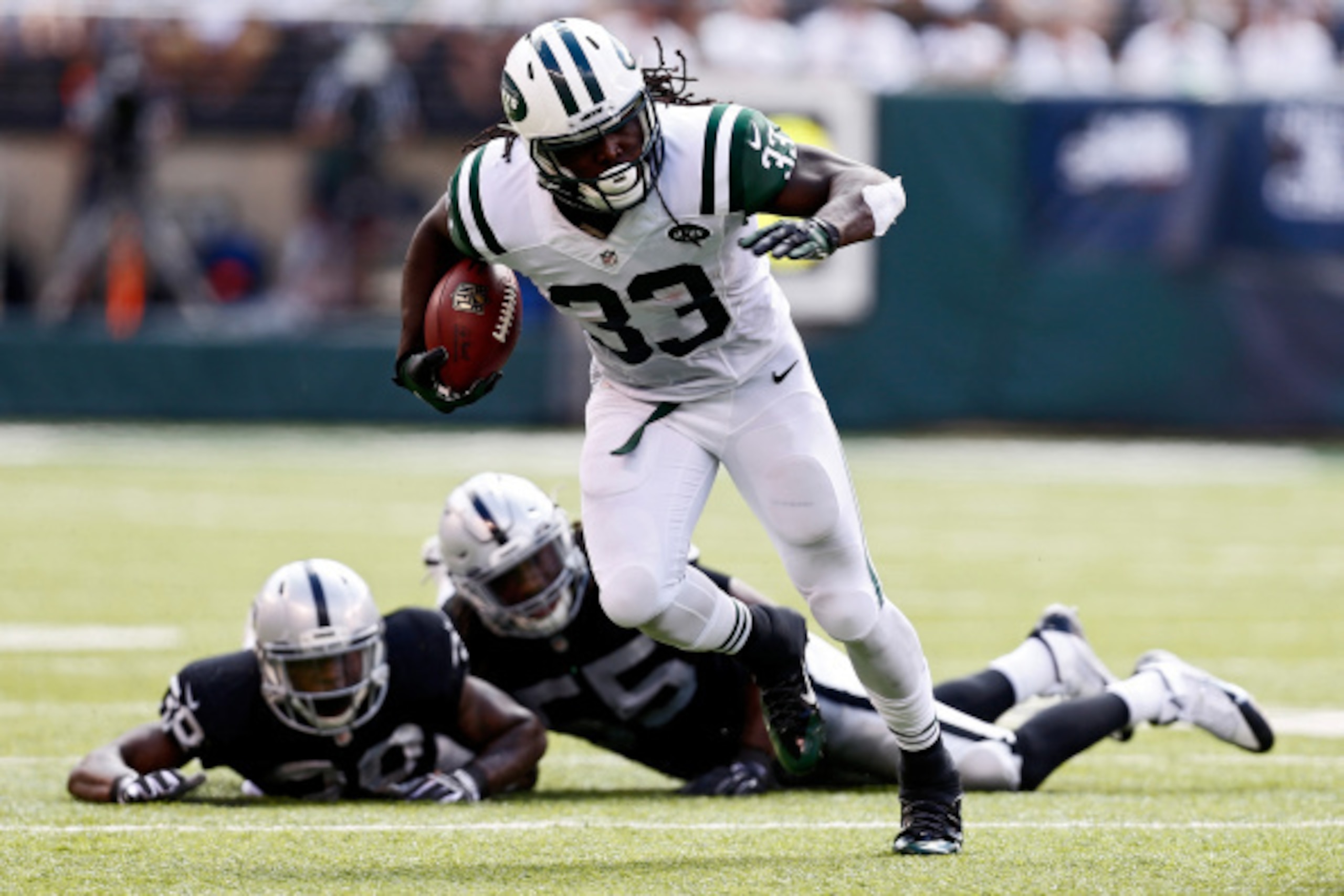 EAST RUTHERFORD, NJ - SEPTEMBER 07: Chris Ivory #33 of the New York Jets rushes after evading tackle attempts by T.J. Carrie #38 and Sio Moore #55 of the Oakland Raiders during the third quarter of a game at MetLife Stadium on September 7, 2014 in Eas EAST RUTHERFORD, NJ - SEPTEMBER 07: Chris Ivory #33 of the New York Jets rushes after evading tackle attempts by T.J. Carrie #38 and Sio Moore #55 of the Oakland Raiders during the third quarter of a game at MetLife Stadium on September 7, 2014 in Eas