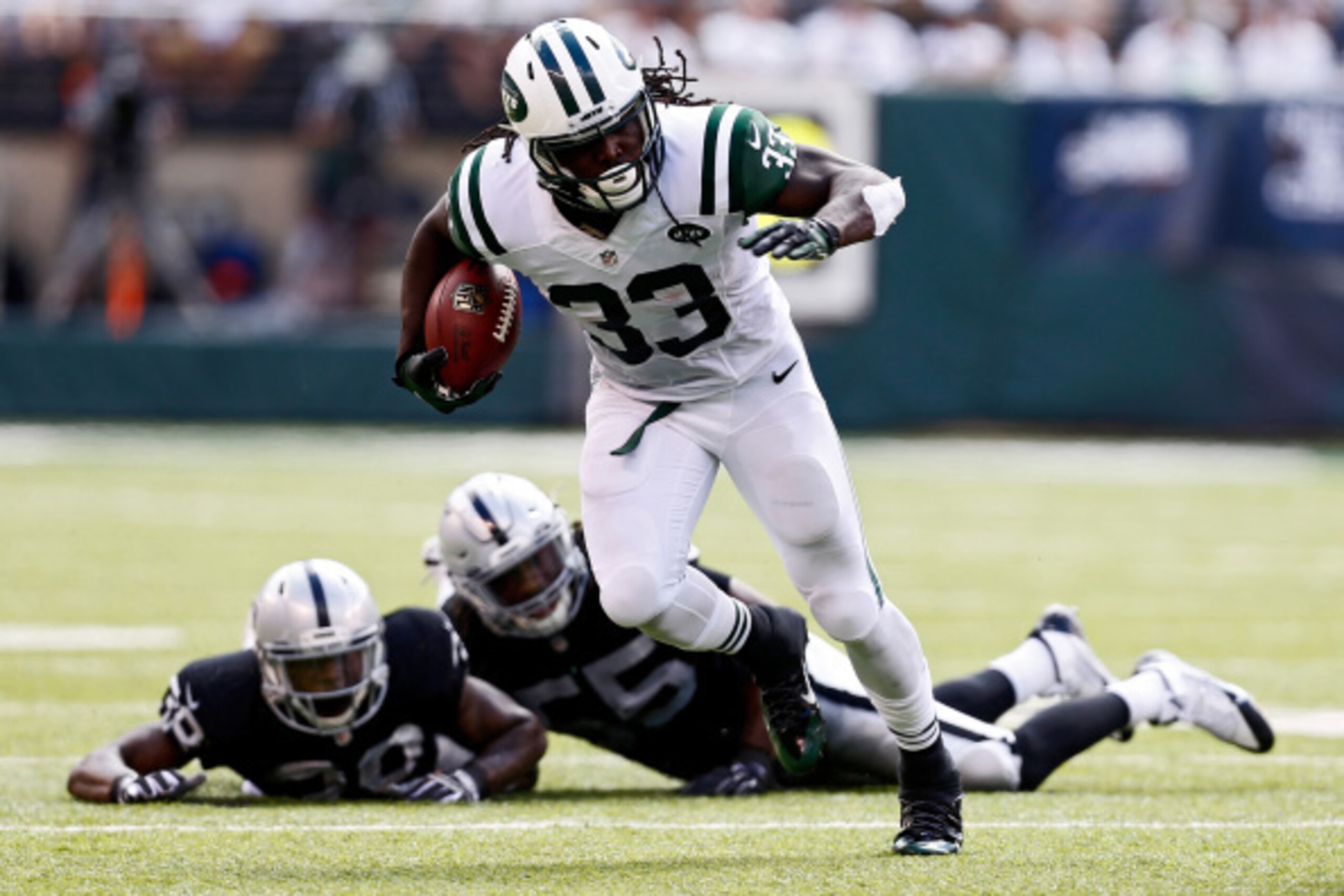 EAST RUTHERFORD, NJ - SEPTEMBER 07:   Chris Ivory #33 of the New York Jets rushes after evading tackle attempts by  T.J. Carrie #38 and  Sio Moore #55 of the Oakland Raiders during the third quarter of a game at MetLife Stadium on September 7, 2014 in Eas