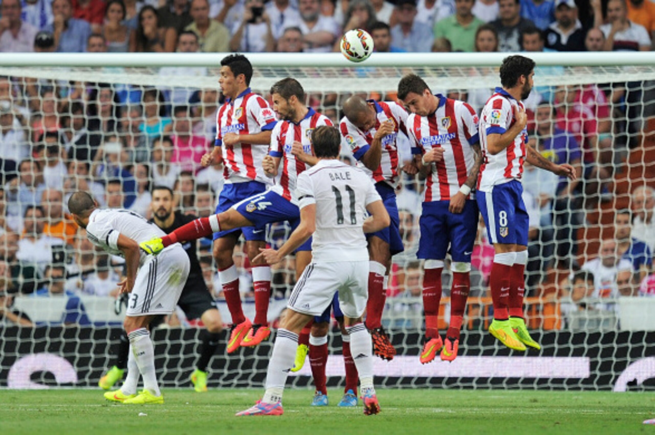 MADRID, SPAIN - SEPTEMBER 13:  Gareth Bale of Real Madrid shoots a free kick over the Atletico  de Madrid wall of defenders during the La Liga match between Real Madrid and Atletico de Madrid at Estadio Santiago Bernabeu on September 13, 2014 in Madrid, S