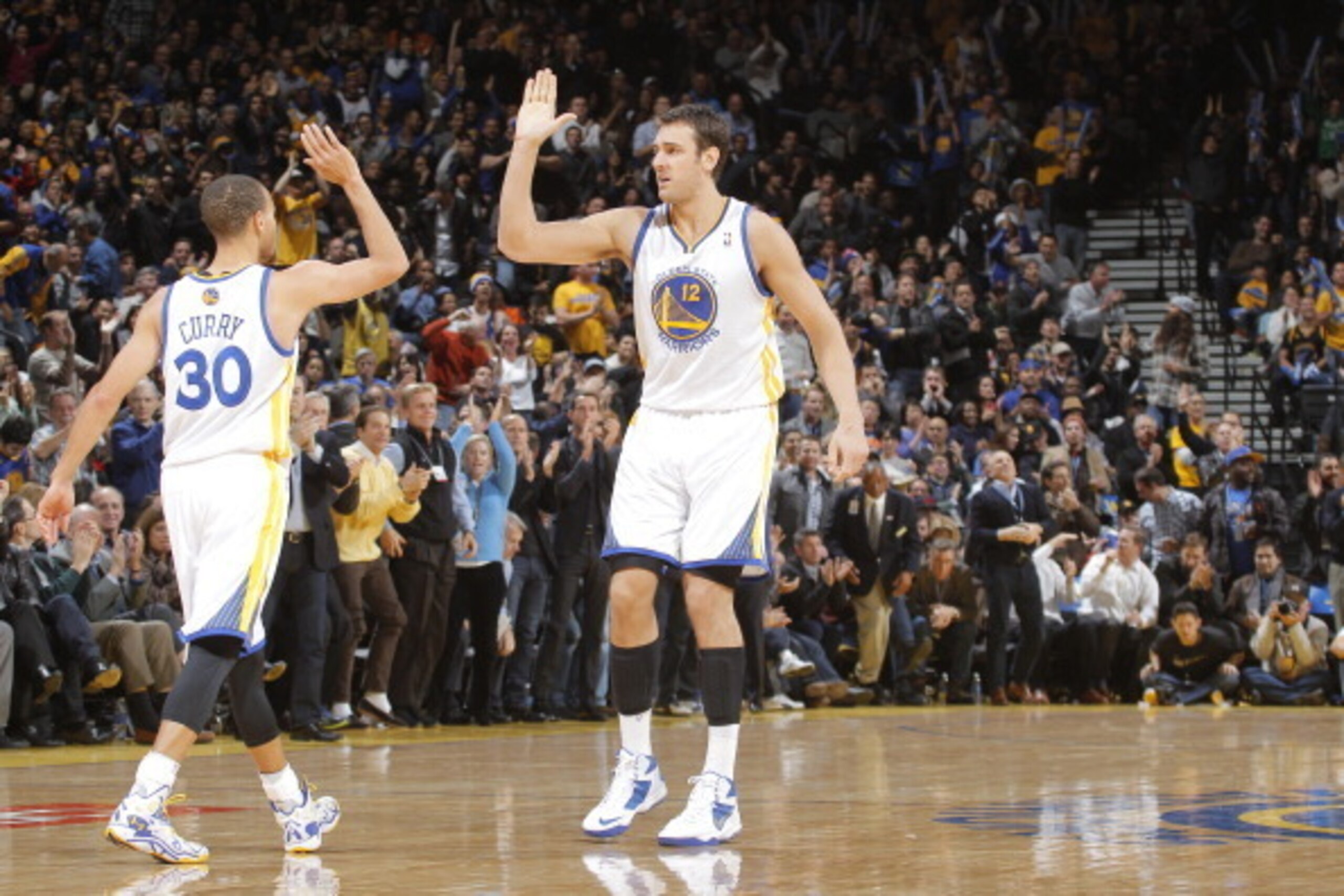 OAKLAND, CA - DECEMBER 11: Stephen Curry #30 of the Golden State Warriors high fives teammate Andrew Bogut #12 during the game against the Dallas Mavericks on December 11, 2013 at Oracle Arena in Oakland, California. NOTE TO USER: User expressly acknowled OAKLAND, CA - DECEMBER 11: Stephen Curry #30 of the Golden State Warriors high fives teammate Andrew Bogut #12 during the game against the Dallas Mavericks on December 11, 2013 at Oracle Arena in Oakland, California. NOTE TO USER: User expressly acknowled