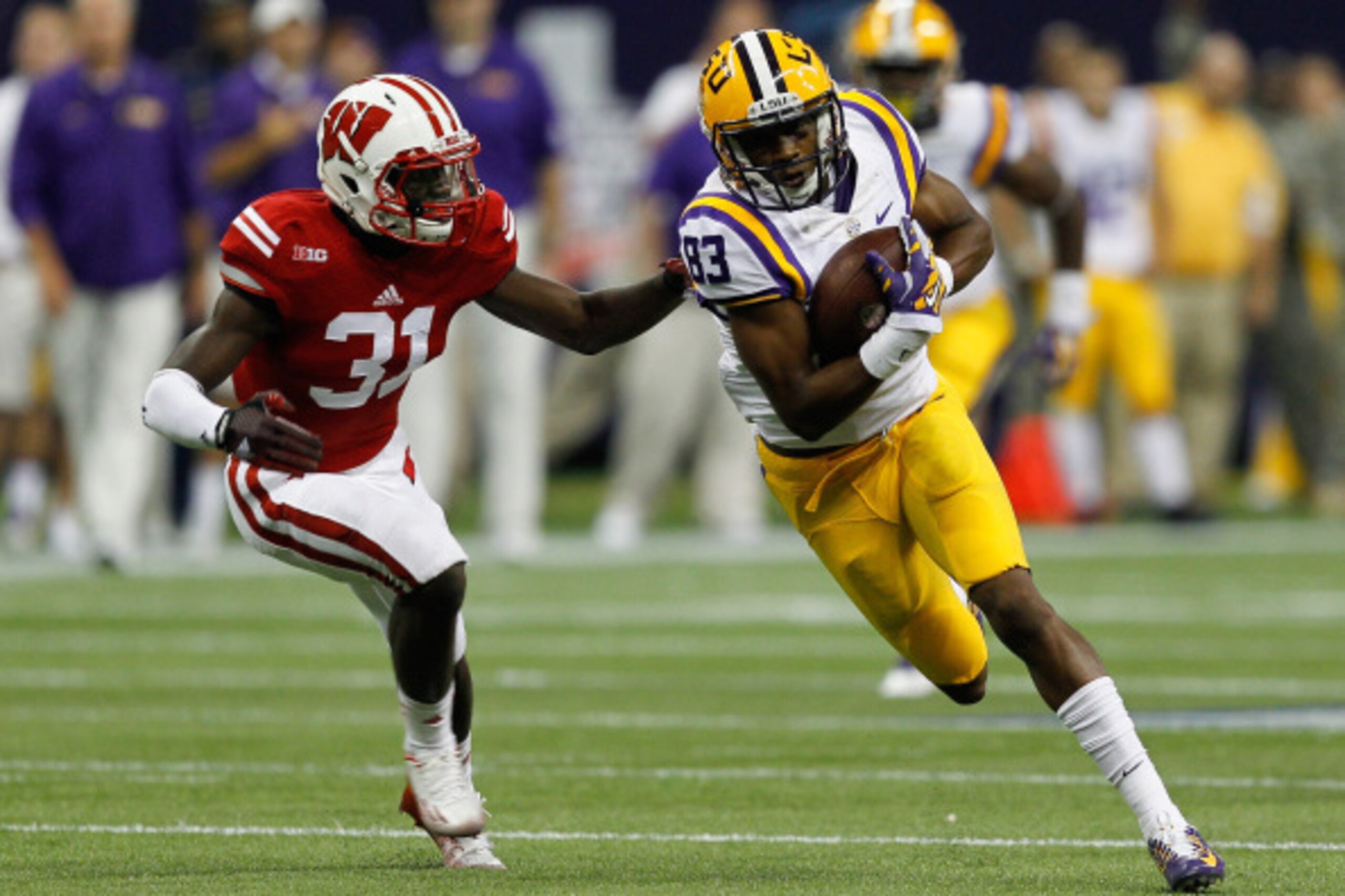 HOUSTON, TX - AUGUST 30:  Travin Dural #83 of the LSU Tigers runs with the ball after a reception as Lubern Figaro #31 of the Wisconsin Badgers attempts a tackle at NRG Stadium on August 30, 2014 in Houston, Texas.  (Photo by Bob Levey/Getty Images)
