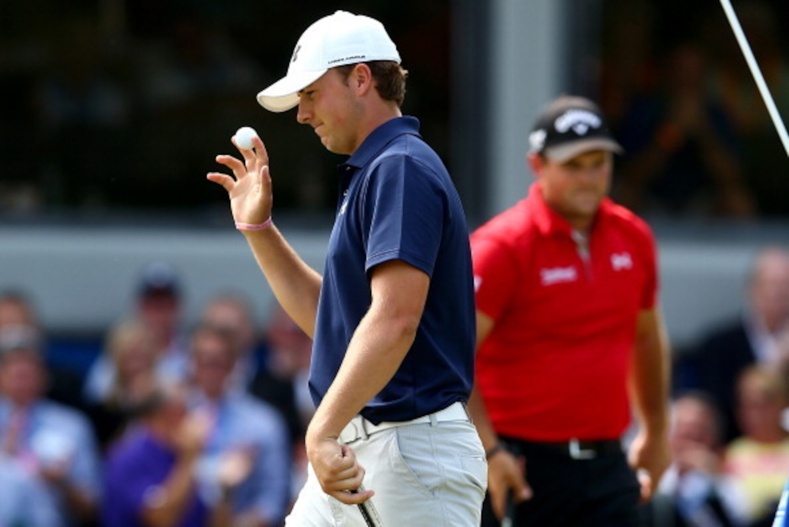 GREENSBORO, NC - AUGUST 18:  (L-R) Jordan Spieth waves to the crowd as Patrick Reed watches on during their playoff on the 18th hole in the final round of the Wyndham Championship at Sedgefield Country Club on August 18, 2013 in Greensboro, North Carolina