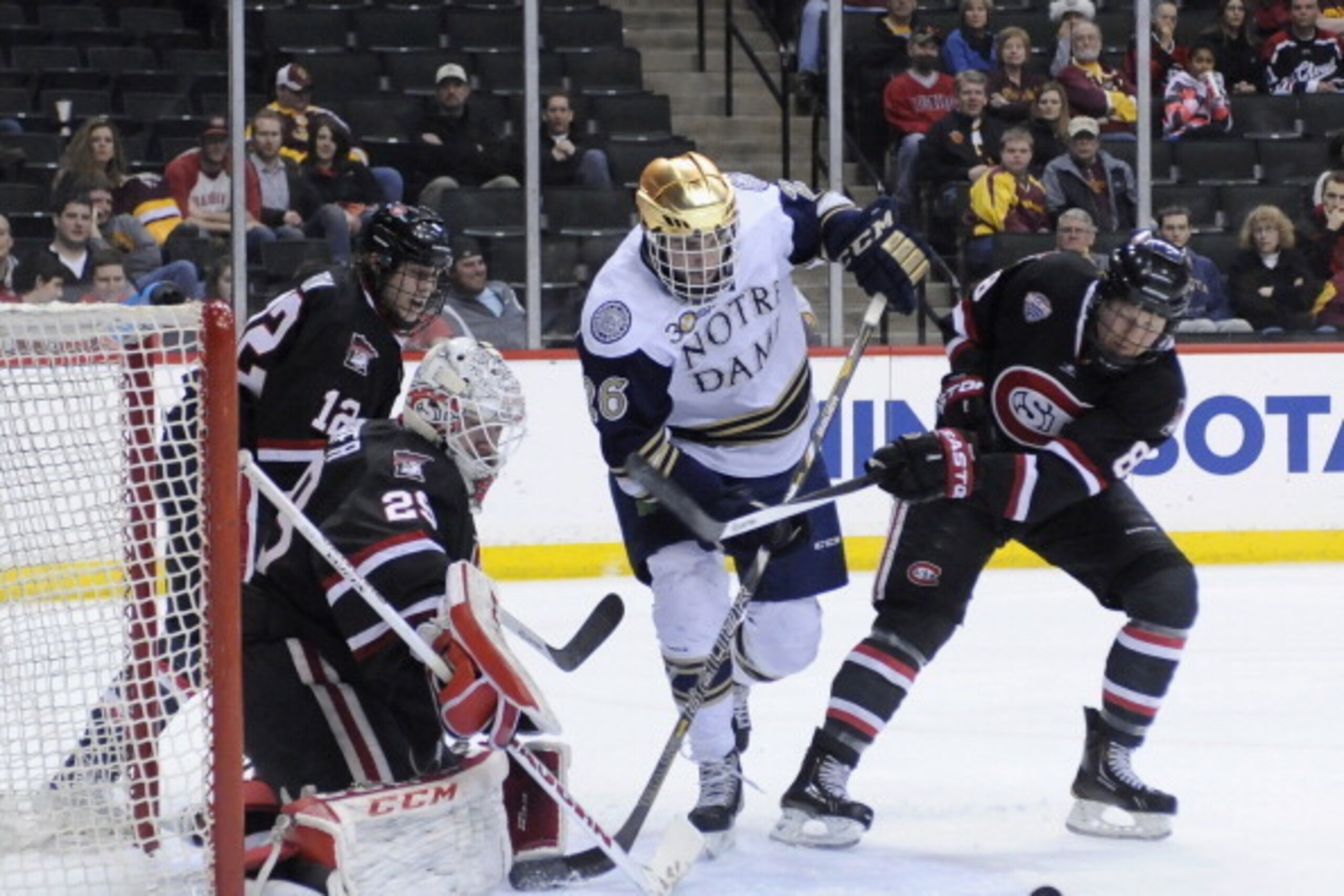 ST PAUL, MN - MARCH 29: Steven Fogarty #26 of the Notre Dame Fighting Irish and Cory Thorson #8 of the St. Cloud State Huskies skate after a puck deflected by Ryan Faragher #29 of the St. Cloud State Huskies during the second period of the West Regional g
