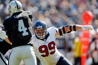 OAKLAND, CA - SEPTEMBER 14:  Quarterback Derek Carr #4 of the Oakland Raiders throws as he takes a hit from J.J. Watt #99 of the Houston Texans in the second quarter on September 14, 2014 at O.co Coliseum in Oakland, California.  (Photo by Brian Bahr/Gett