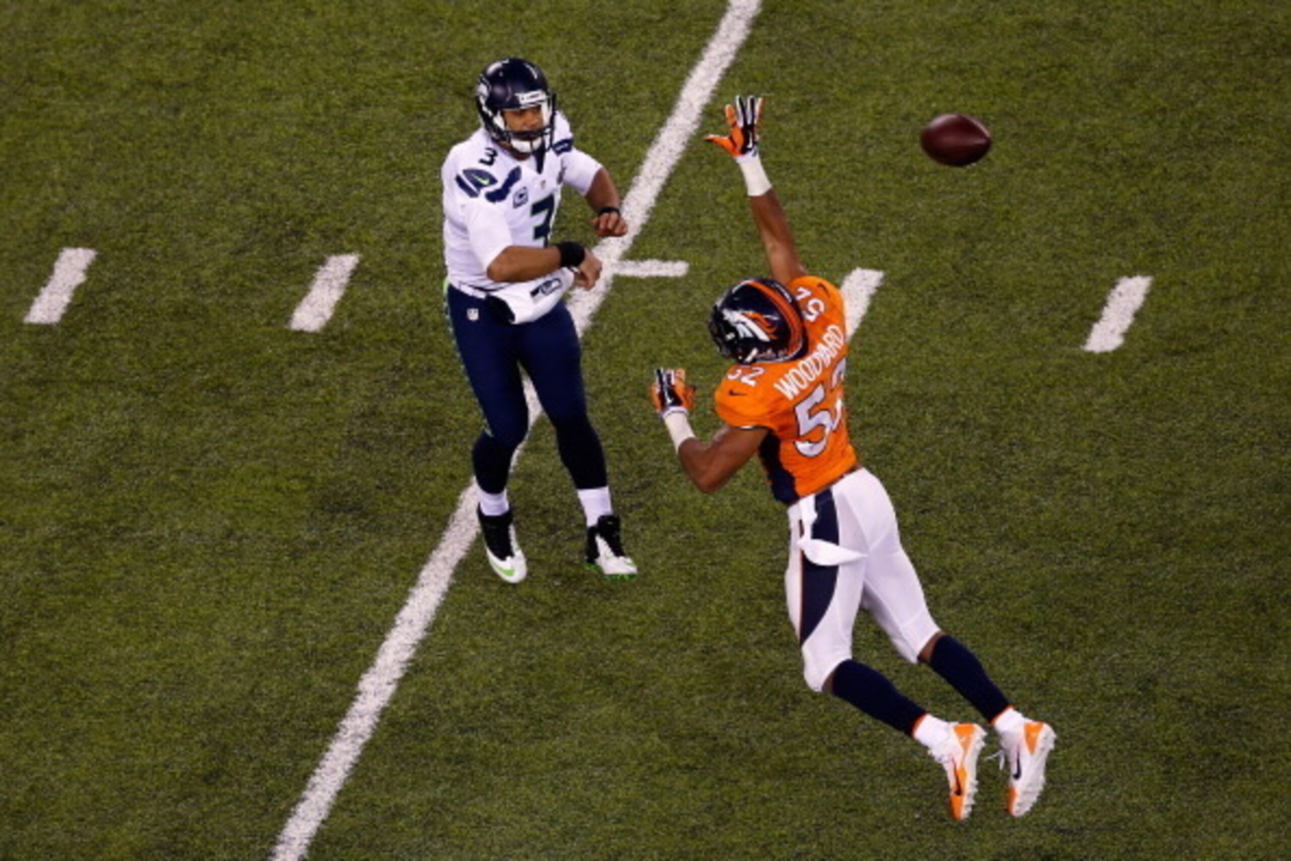 EAST RUTHERFORD, NJ - FEBRUARY 02:  Russell Wilson #3 of the Seattle Seahawks passes as Wesley Woodyard #52 of the Denver Broncos defends during Super Bowl XLVIII at MetLife Stadium on February 2, 2014 in East Rutherford, New Jersey.  (Photo by Jeff Zelev