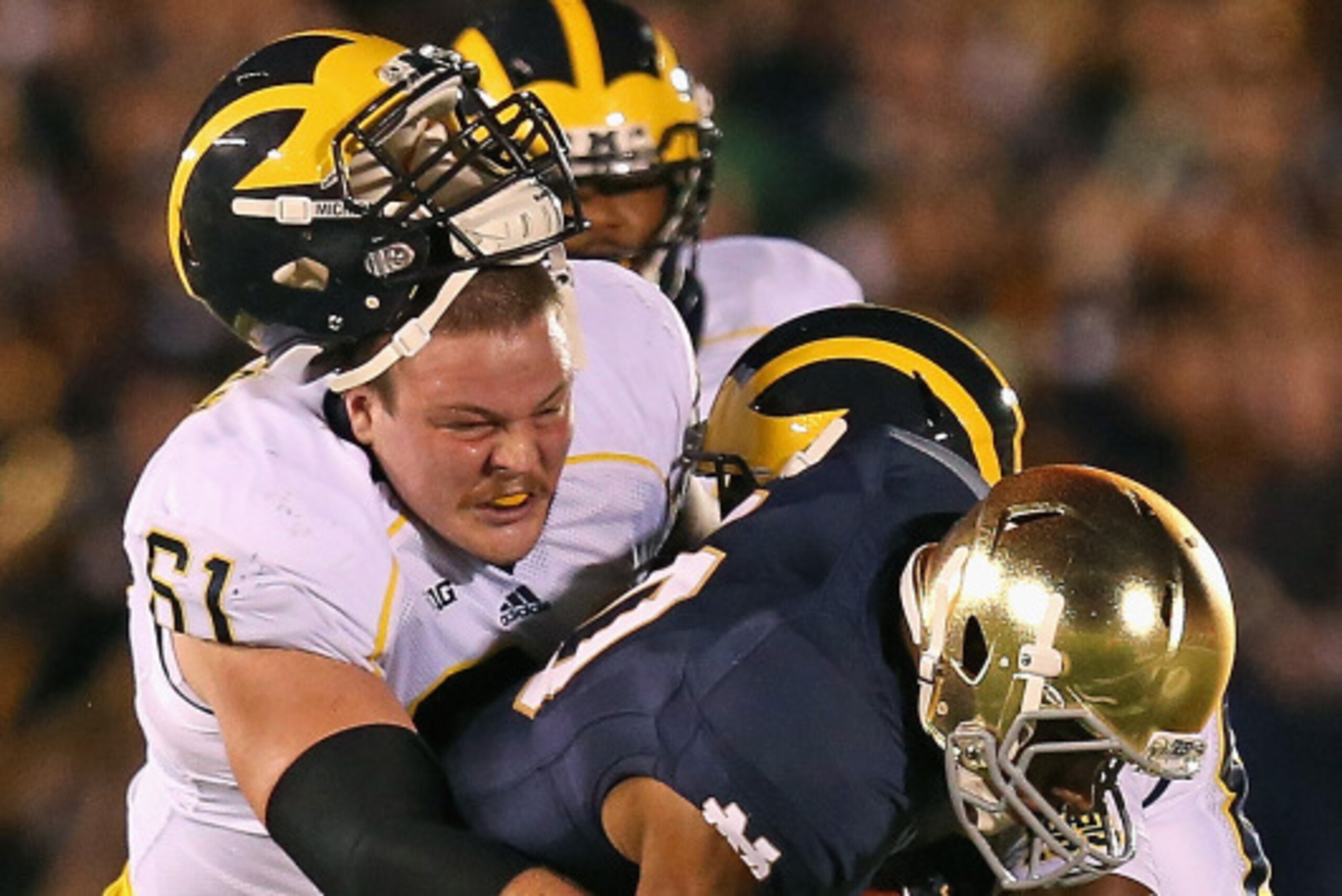 SOUTH BEND, IN - SEPTEMBER 06: Graham Glasgow #51 of the Michigan Wolverines looses his helmet as he and teammate Jehu Chesson #86 try to tackle Max Redfield #210 of the Notre Dame Fighting Irish after Redfiled intercepted a pass at Notre Dame Stadium on 