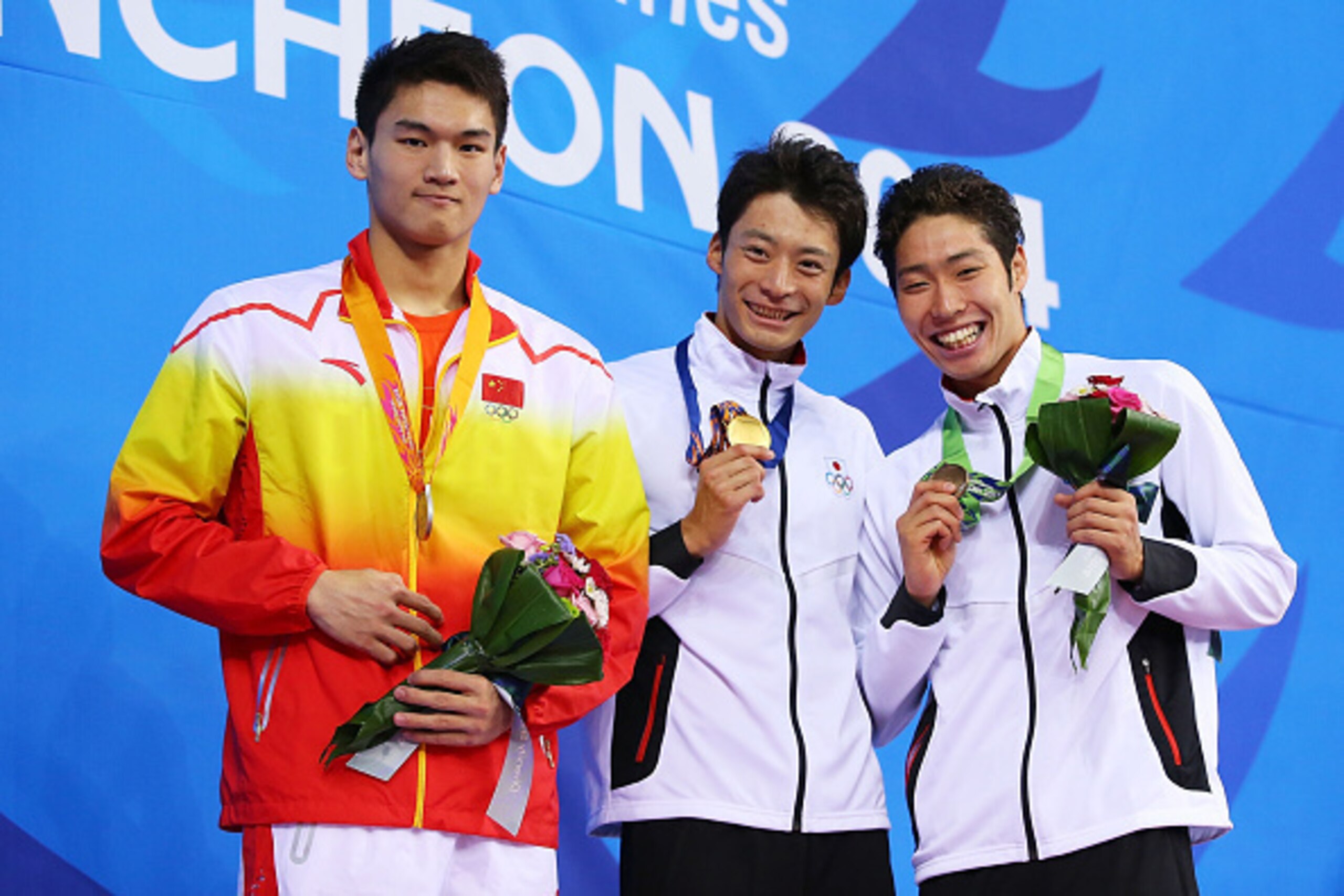 INCHEON, SOUTH KOREA - SEPTEMBER 21:  Gold medalist (C) Ryosuke Irie of Japan, Silver medalist (L) Jiayu Xu of China and Bronze medalist (R) Kosuke Hagino of Japan pose atop the podium after the Men's 100m Backstroke Final during day two of the 2014 Asian