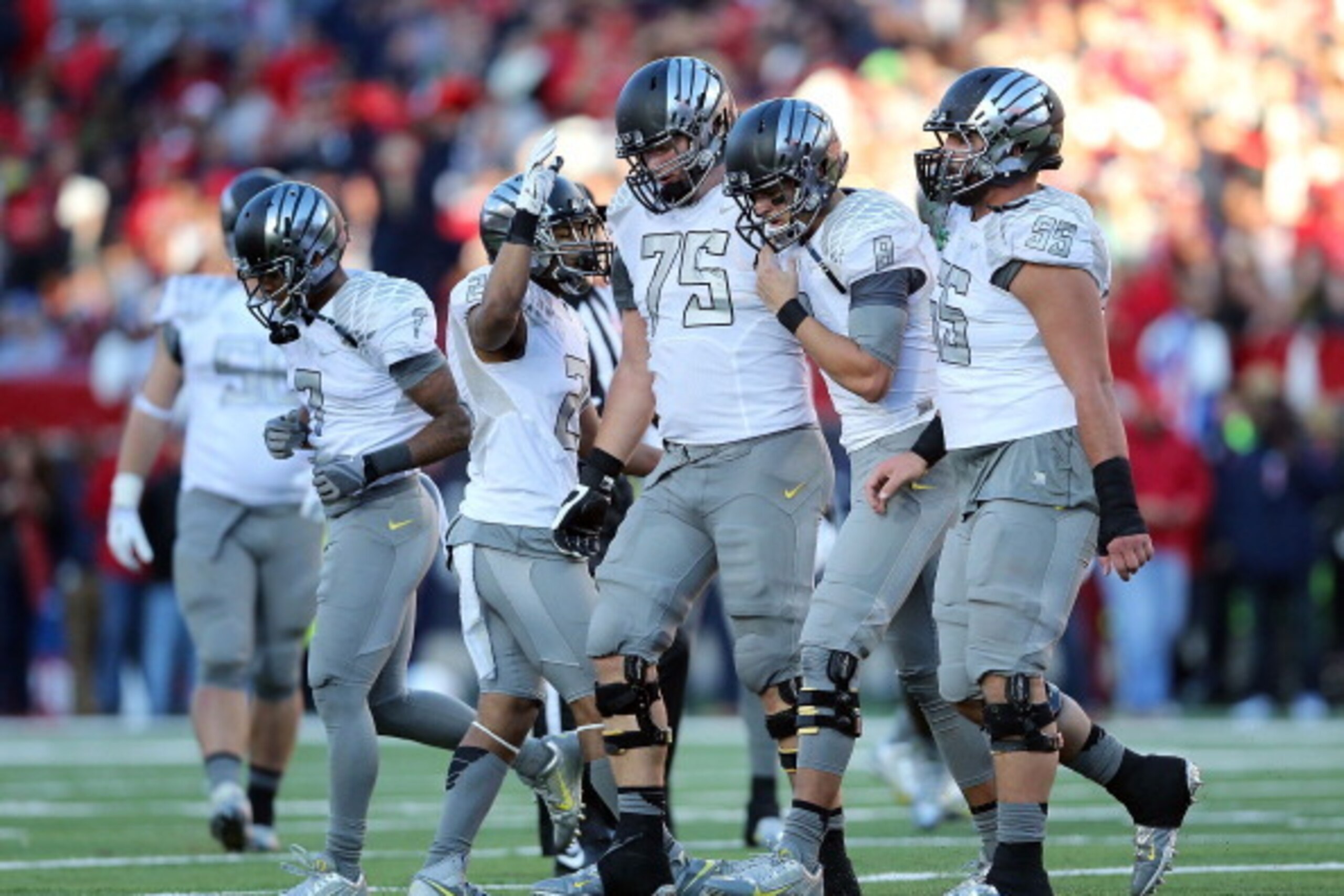 TUCSON, AZ - NOVEMBER 23:  Quarterback Marcus Mariota #8 of the Oregon Ducks is helped off the field by offensive linesman Jake Fisher #75 and offensive linesman Hroniss Grasu #55 after being injured during the fourth quarter of the college football game 