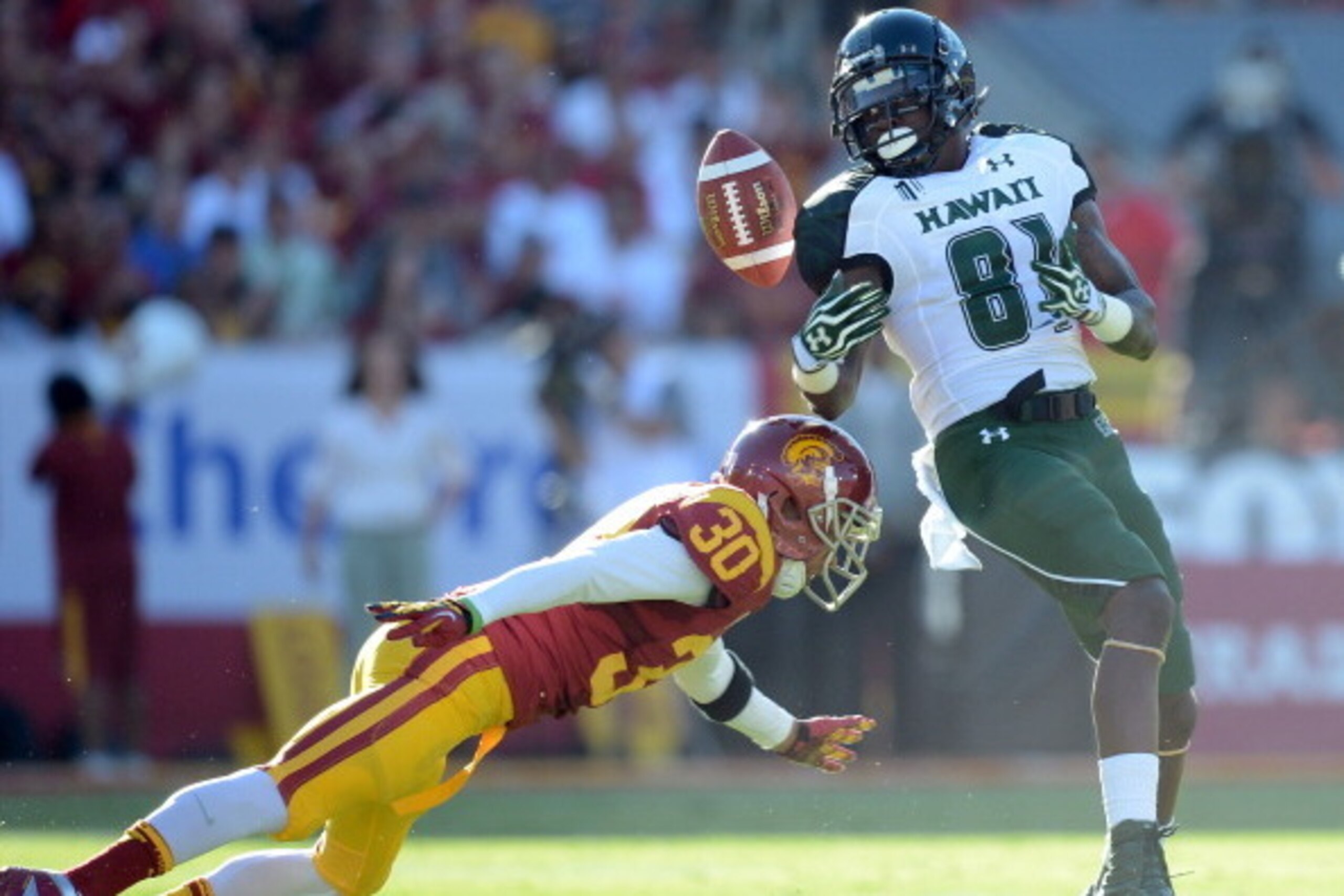 LOS ANGELES, CA - SEPTEMBER 01:  Chris Gant #81 of the Hawaii Warriors juggles as pass as he is tackled by Brian Baucham #30 of the USC Trojans at Los Angeles Coliseum on September 1, 2012 in Los Angeles, California.  (Photo by Harry How/Getty Images)