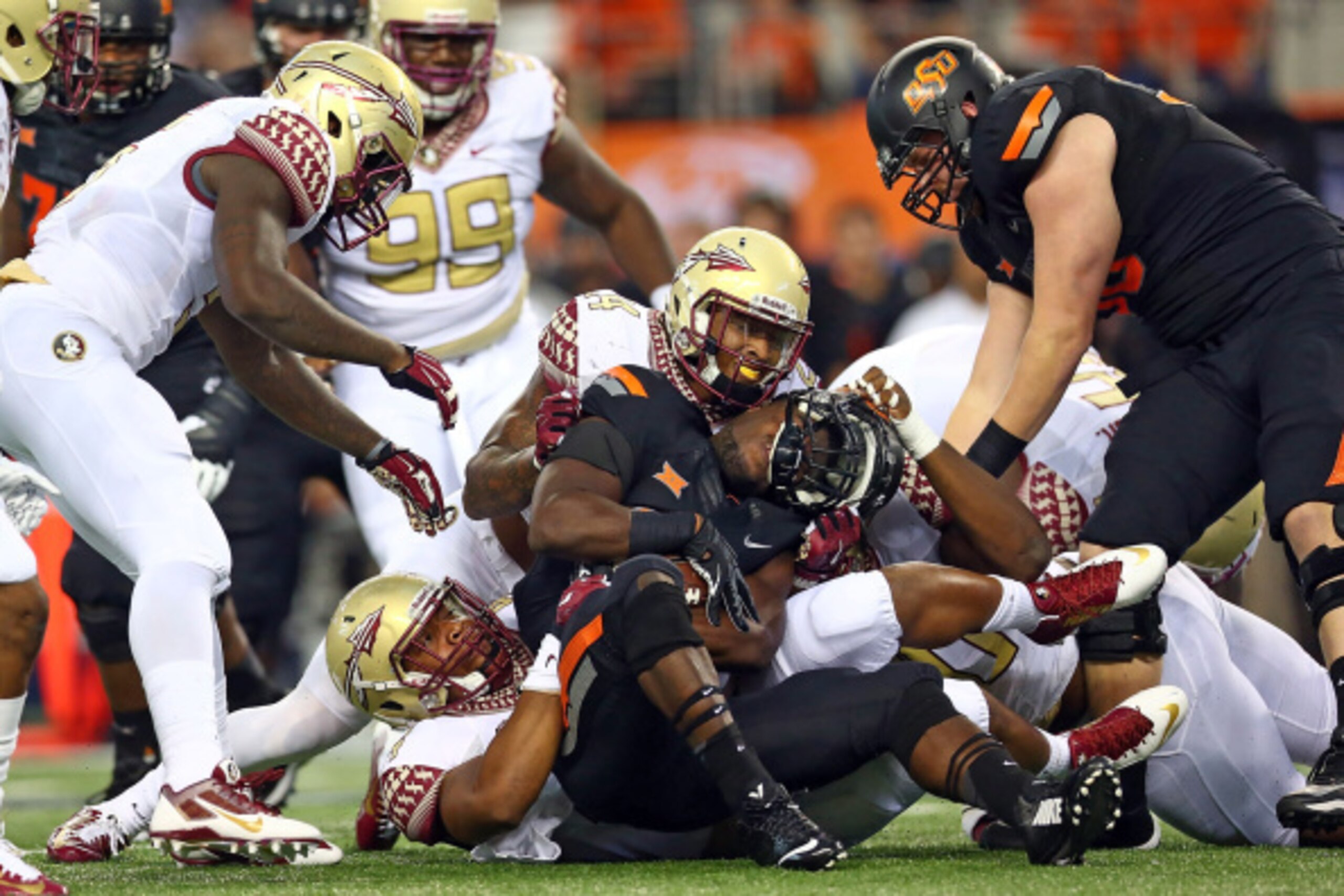 ARLINGTON, TX - AUGUST 30:  Desmond Roland #26 of the Oklahoma State Cowboys is tackled by the  Florida State Seminoles defense in the first half of the Advocare Cowboys Classic at AT&T Stadium on August 30, 2014 in Arlington, Texas.  (Photo by Ronald Mar