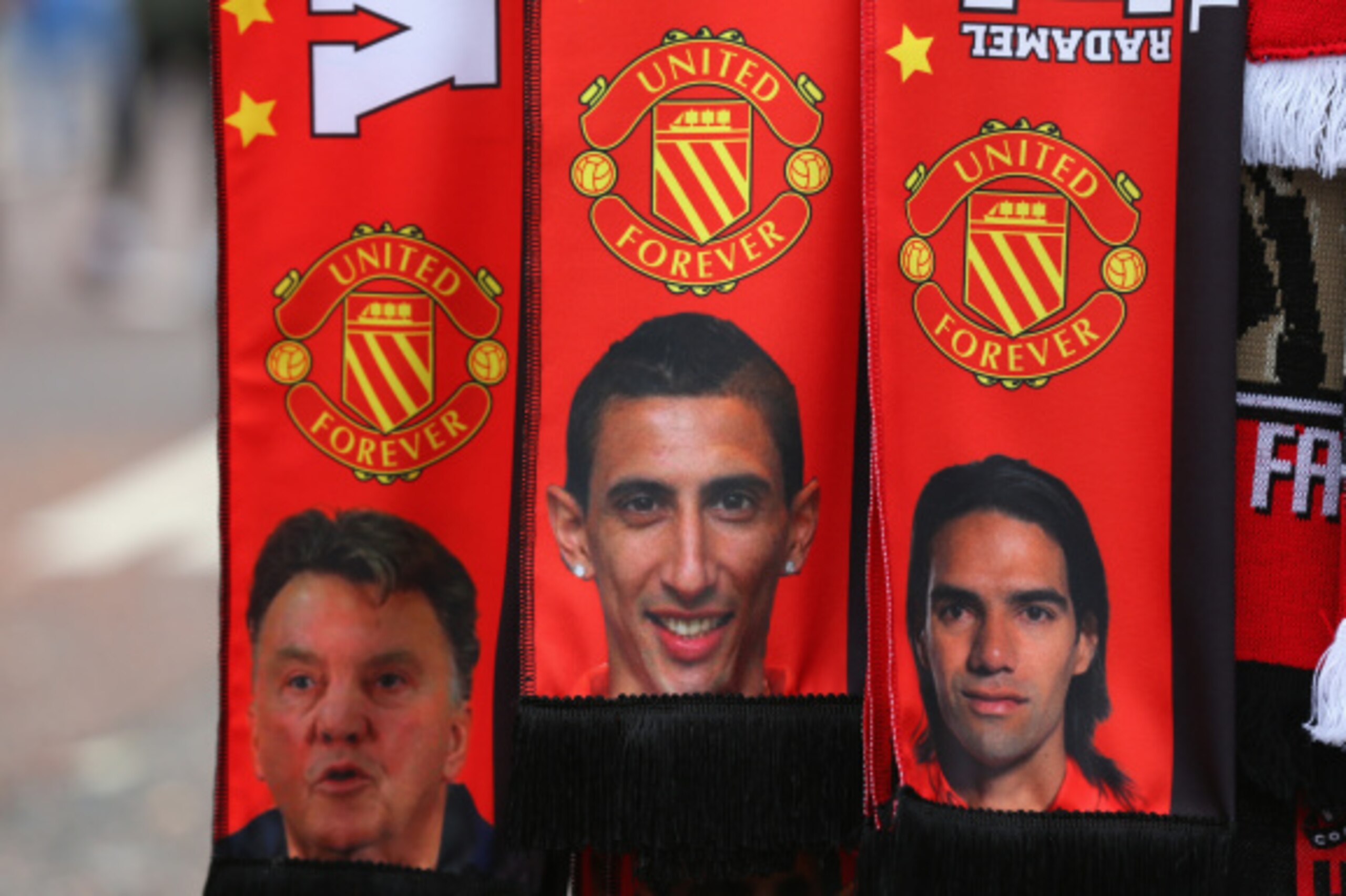 MANCHESTER, ENGLAND - SEPTEMBER 14:  A vendor sells scarves showing  Manager Louis van Gaal and new signings Falcao and Angel Di Maria prior to the Barclays Premier League match between Manchester United and Queens Park Rangers at Old Trafford on Septembe