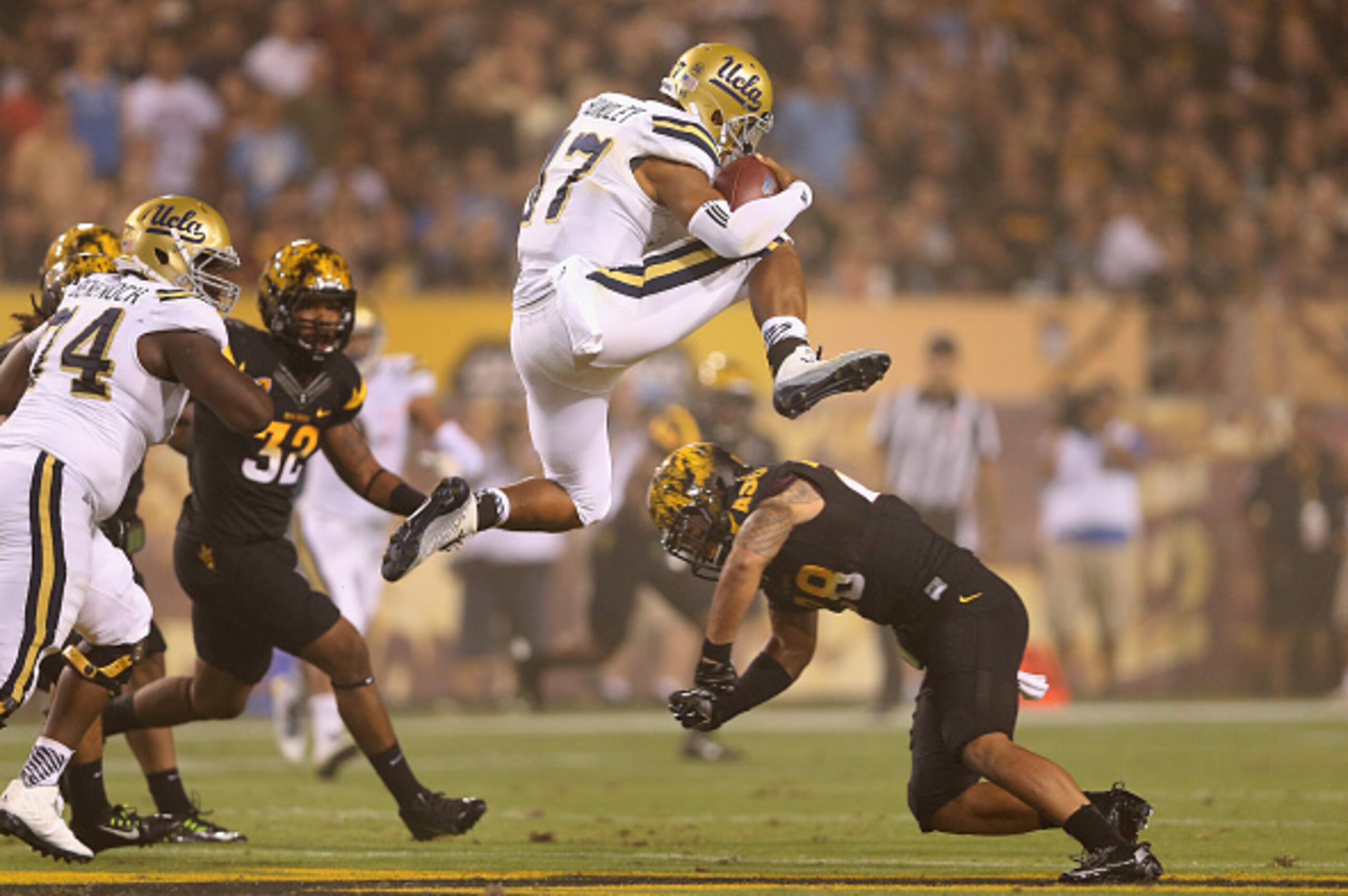 TEMPE, AZ - SEPTEMBER 25:  Quarterback Brett Hundley #17 of the UCLA Bruins leaps over llinebacker Viliami Laiu Moeakiola #28 of the Arizona State Sun Devils as he rushes the football during the second quarter of the college football game at Sun Devil Sta
