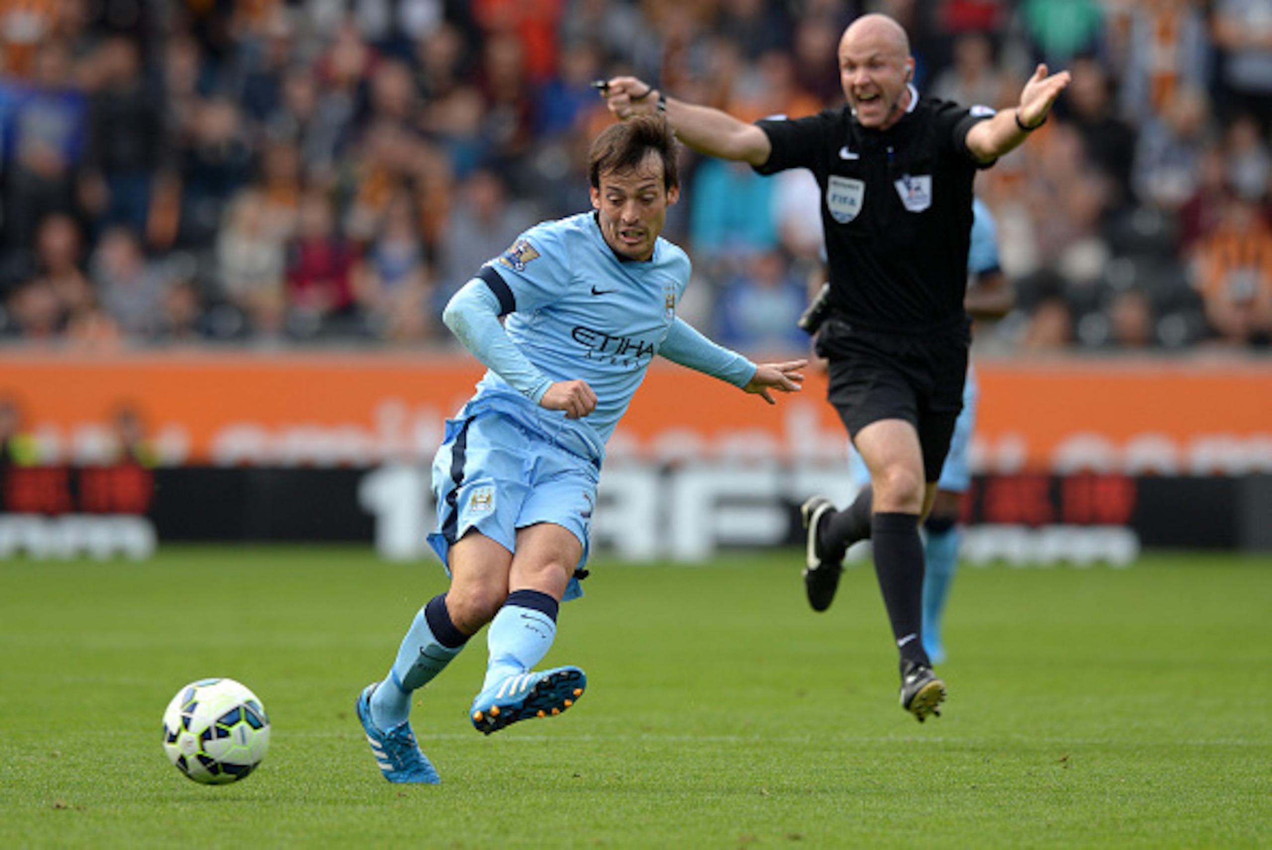 HULL, ENGLAND - SEPTEMBER 27:  David Silva of Manchester City passes the ball as referee Anthony Taylor waves play on during the Barclays Premier League match between Hull City and Manchester City at KC Stadium on September 27, 2014 in Hull, England.  (Ph