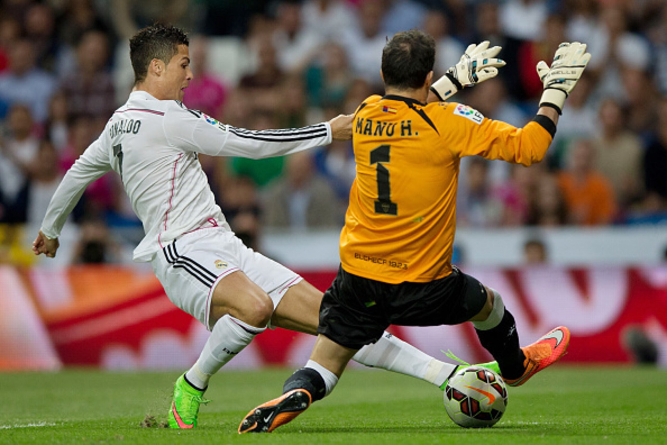 MADRID, SPAIN - SEPTEMBER 23: Cristiano Ronaldo (L) of Real Madrid CF competes for the ball with goalkeeper Manu Herrera of  Elche FC during the La Liga match between Real Madrid CF and Elche CF at Estadio Santiago Bernabeu on September 23, 2014 in Madrid