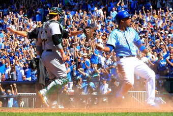 KANSAS CITY, MO - AUGUST 14:  Alcides Escobar #2 of the Kansas City Royals celebrates after sliding into home plate to score during the 7th inning of the game against the Oakland Athletics at Kauffman Stadium on August 14, 2014 in Kansas City, Missouri.  