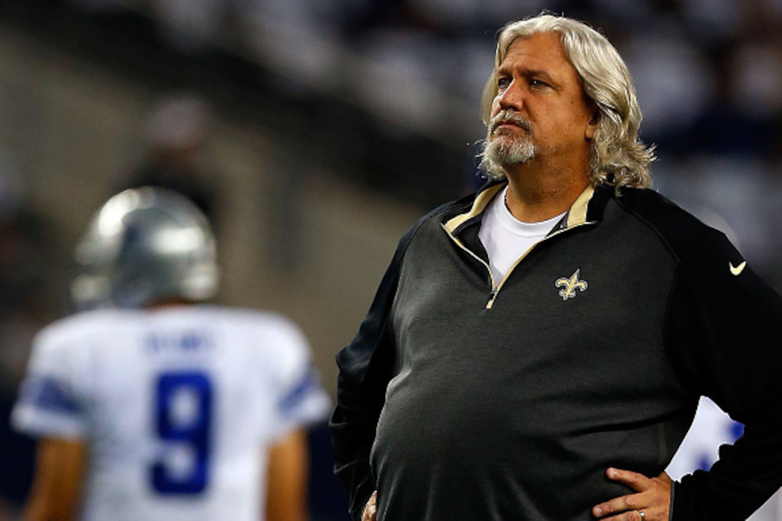 ARLINGTON, TX - SEPTEMBER 28: Defensive Coordinator Rob Ryan of the New Orleans Saints walks the field as Tony Romo #9 of the Dallas Cowboys stands in the background before the start of the game at AT&T Stadium on September 28, 2014 in Arlington, Texas.  