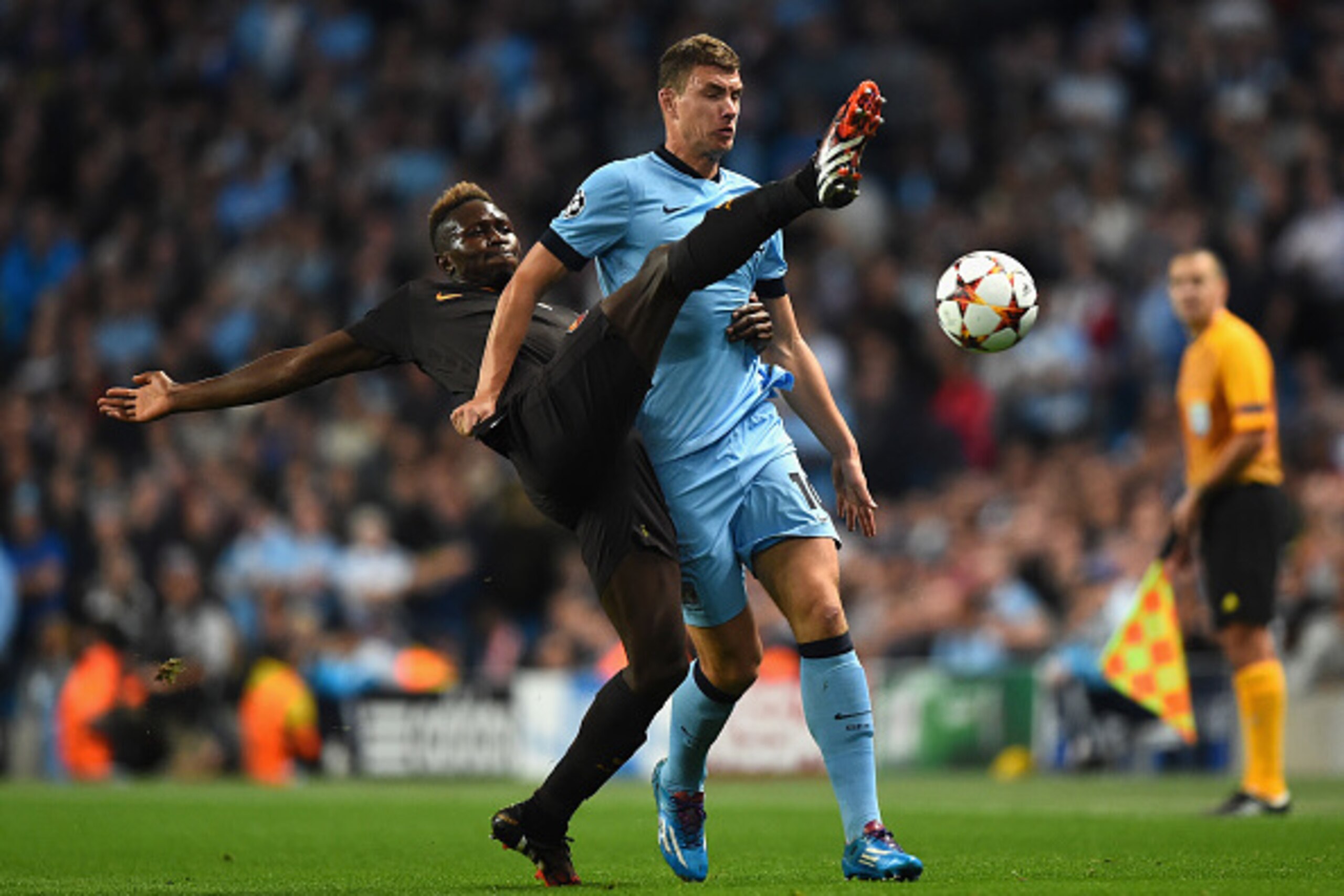 MANCHESTER, ENGLAND - SEPTEMBER 30:  Mapou Yanga-Mbiwa of AS Roma competes with Edin Dzeko of Manchester City during the UEFA Champions League Group E match between Manchester City FC and AS Roma  on September 30, 2014 in Manchester, United Kingdom.  (Pho