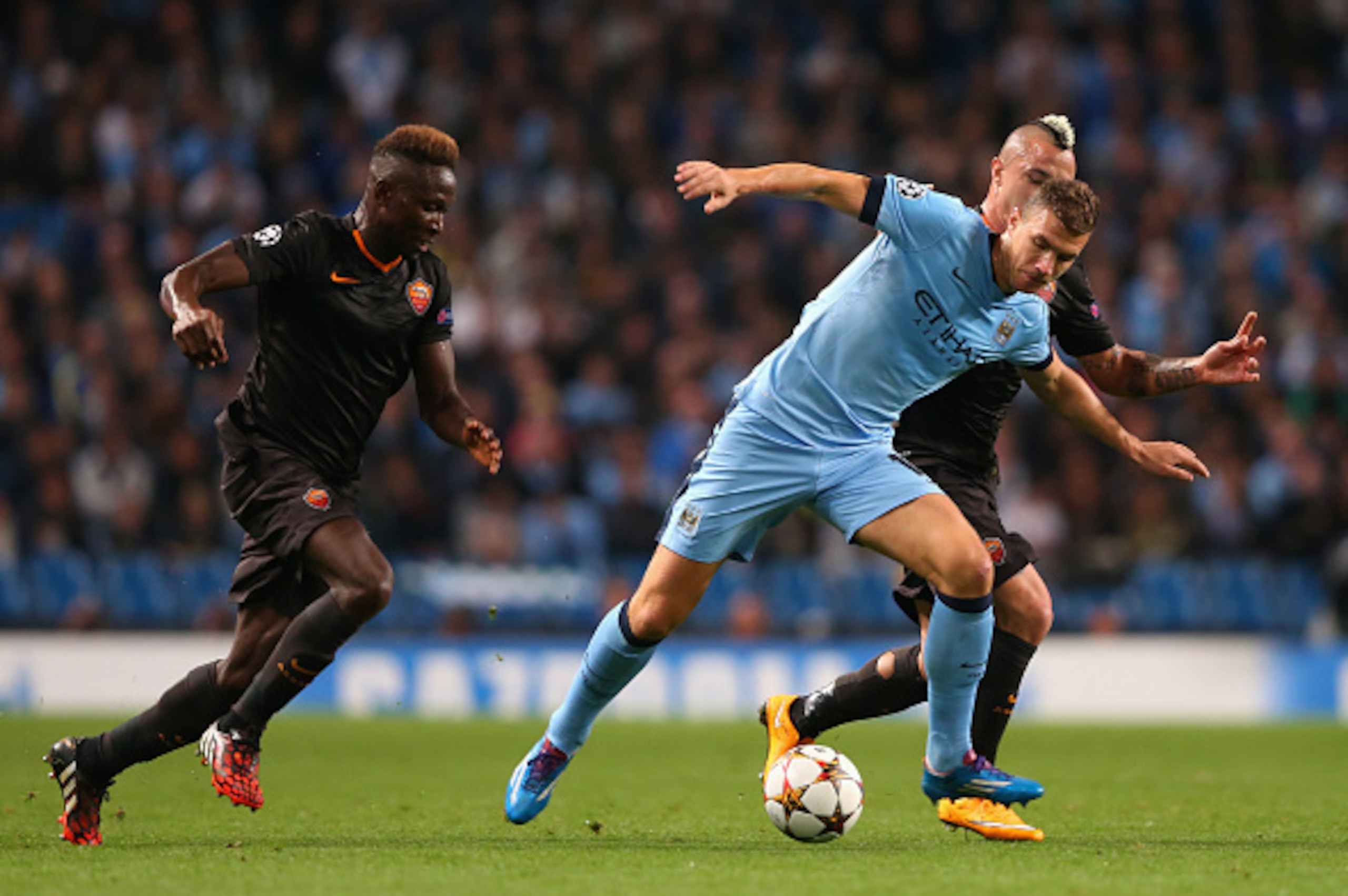 MANCHESTER, ENGLAND - SEPTEMBER 30:  Radja Nainggolan and Mapou Yanga-Mbiwa (L) of AS Roma challenge Edin Dzeko of Manchester City during the UEFA Champions League Group E match between Manchester City FC and AS Roma  on September 30, 2014 in Manchester, 