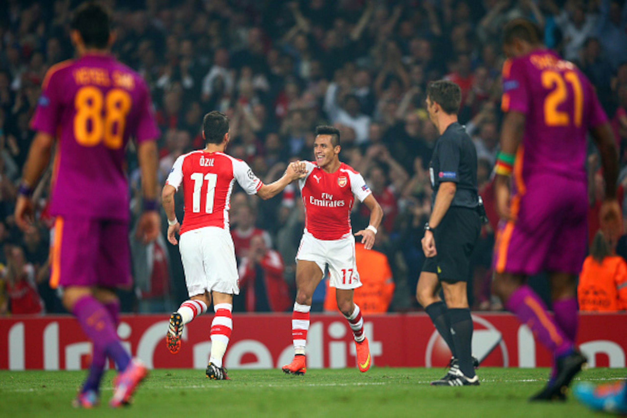 LONDON, ENGLAND - OCTOBER 01:  Alexis Sanchez of Arsenal celebrates with team-mate Mesut Oezil after scoring his team's third goal during the UEFA Champions League group D match between Arsenal FC and Galatasaray AS at Emirates Stadium on October 1, 2014 