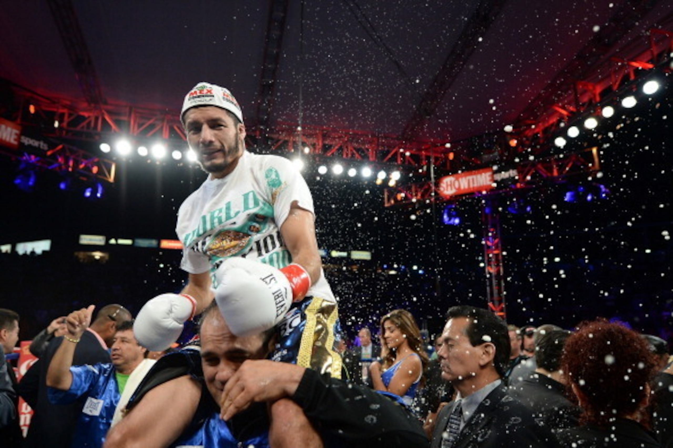 CARSON, CA - AUGUST 24:  Jhonny Gonzalez ducks a thrown beer from the crowd as he celebrates his first round knockout of Abner Mares during the WBC Featherweight Title Fight at the StubHub Center on August 24, 2013 in Carson, California.  (Photo by Harry 