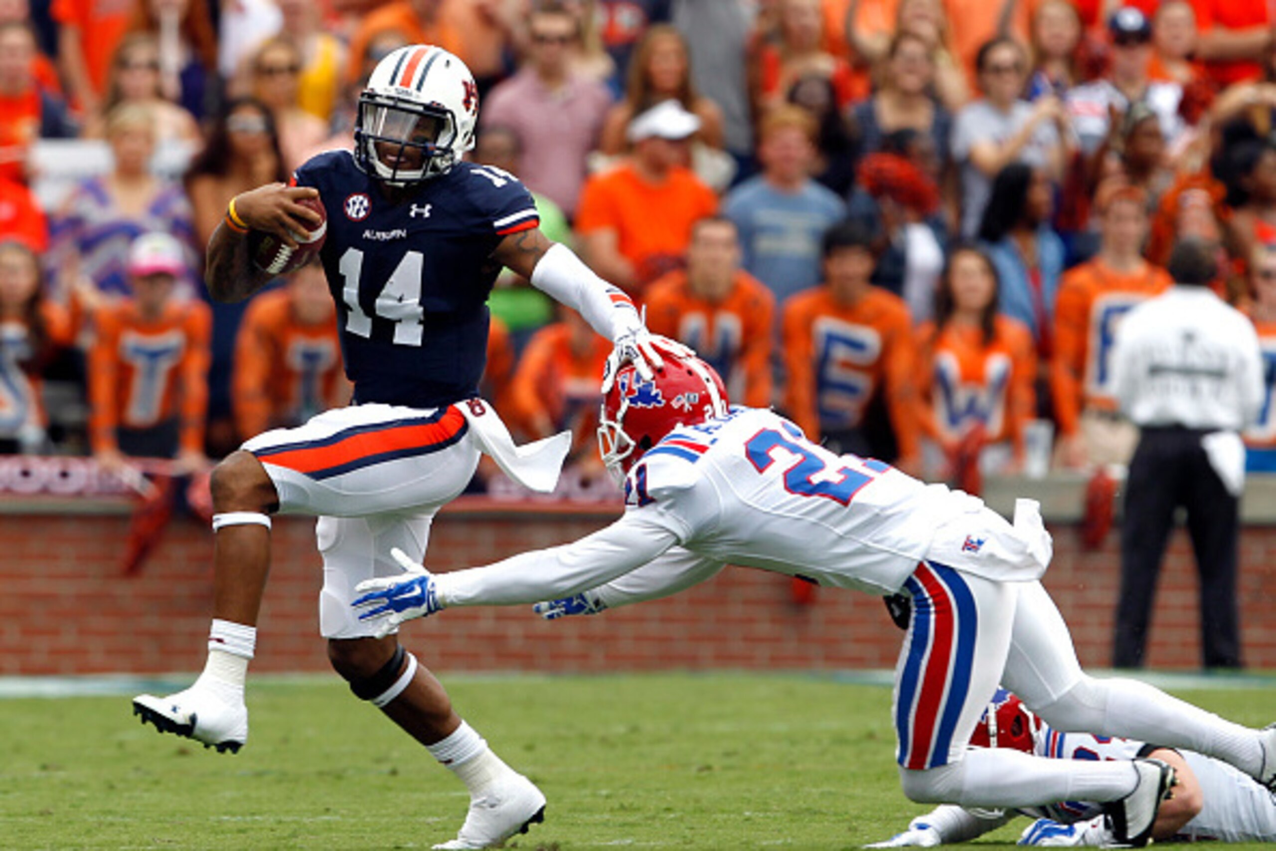AUBURN, AL - SEPTEMBER 27:  Quarterback Nick Marshall #14 of the Auburn Tigers stiff arms defensive back Adairius Barnes #21 of the Louisiana Tech Bulldogs as he scrambles at Jordan Hare Stadium on September 27, 2014, in Auburn, Alabama. (Photo by Butch D