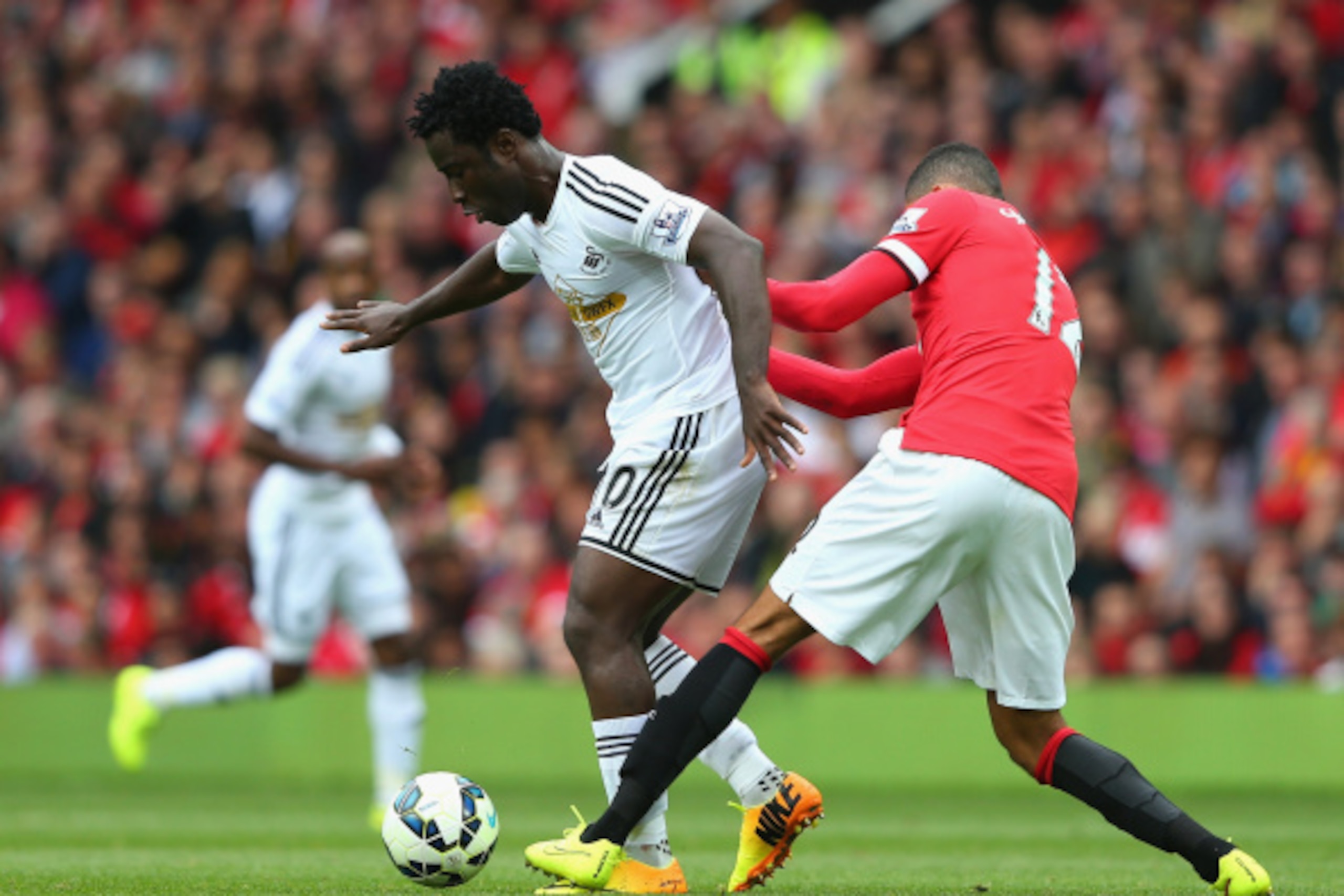 MANCHESTER, ENGLAND - AUGUST 16:  Wilfried Bony of Swansea City is challenged by Chris Smalling of Manchester United during the Barclays Premier League match between Manchester United and Swansea City at Old Trafford on August 16, 2014 in Manchester, Engl
